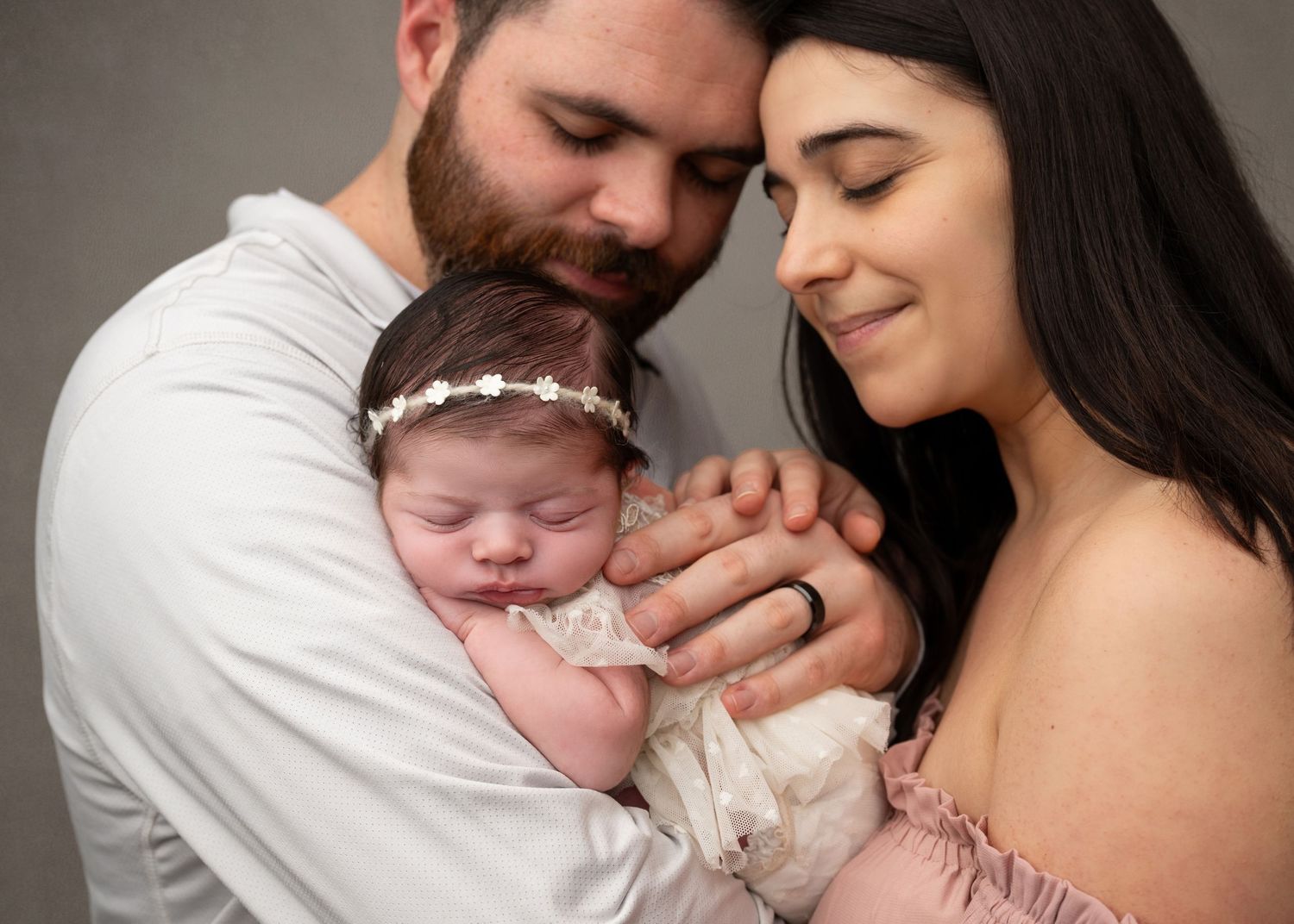 Parents cuddling their newborn baby during a studio newborn photography session in Linden, New Jersey.