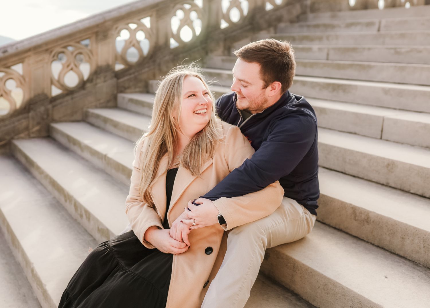 Romantic couple sitting and embracing on stone steps during a sweet engagement photo session.