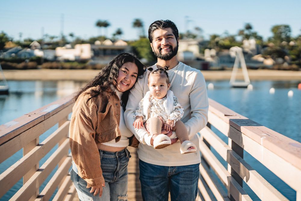 Happy family posing together on wooden pier with marina in background.