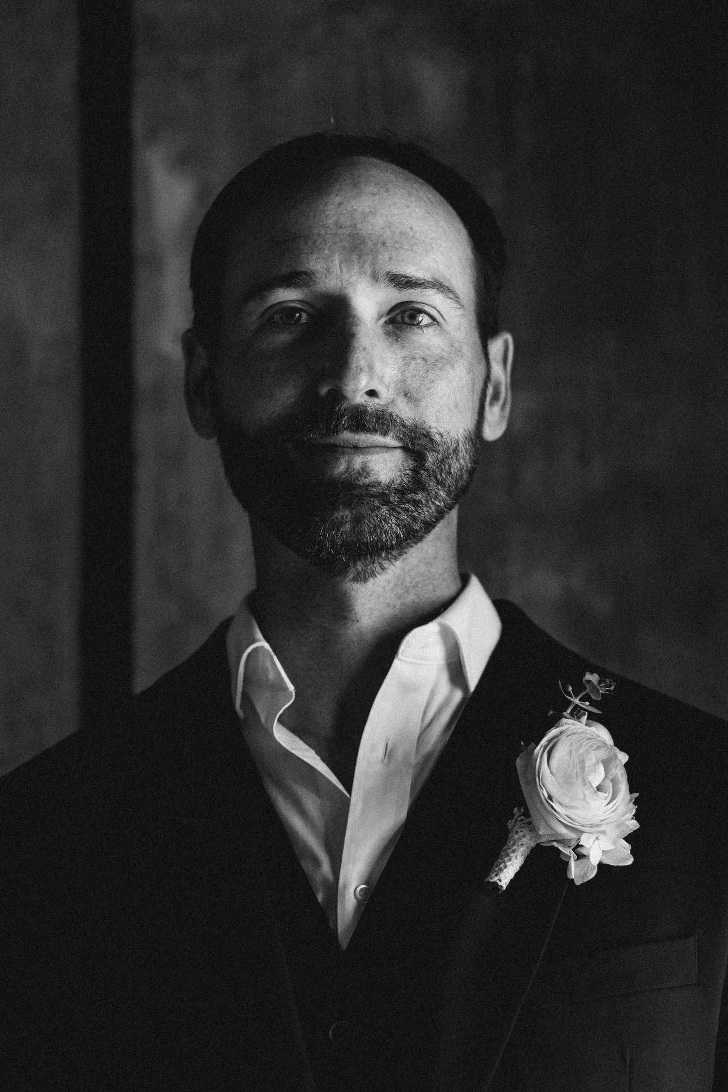 A classic black and white portrait with a boutonniere in a formal suit.