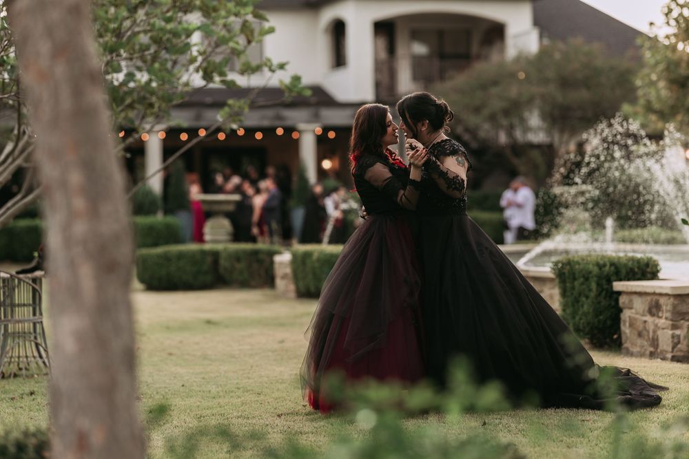 Outdoor wedding reception setup with string lights and trees in a garden setting at dusk.
