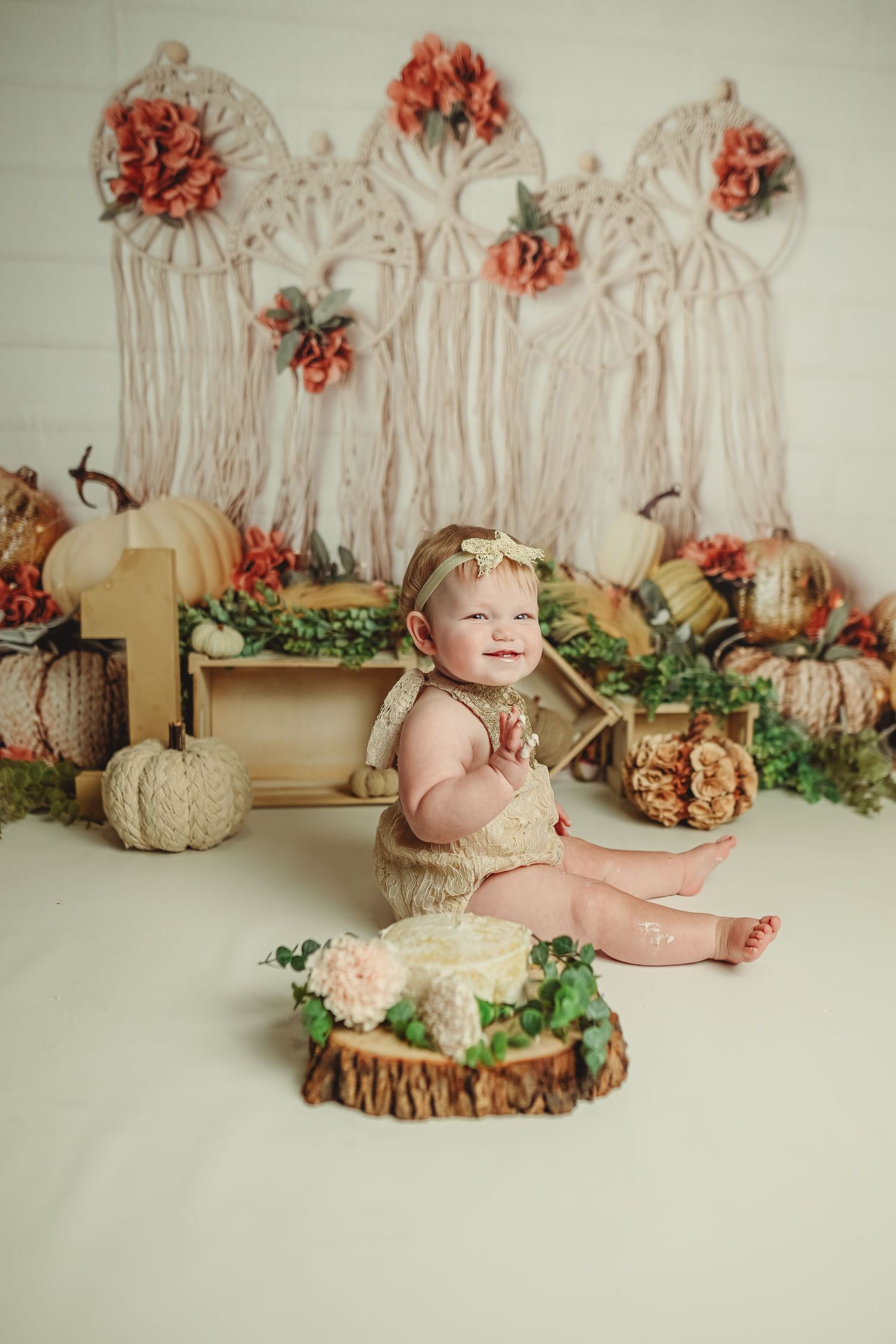 Baby photography setup with autumn decorations featuring pumpkins and coral flowers.