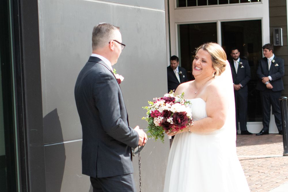 A wedding ceremony moment outside with a couple exchanging vows and a beautiful burgundy bouquet.