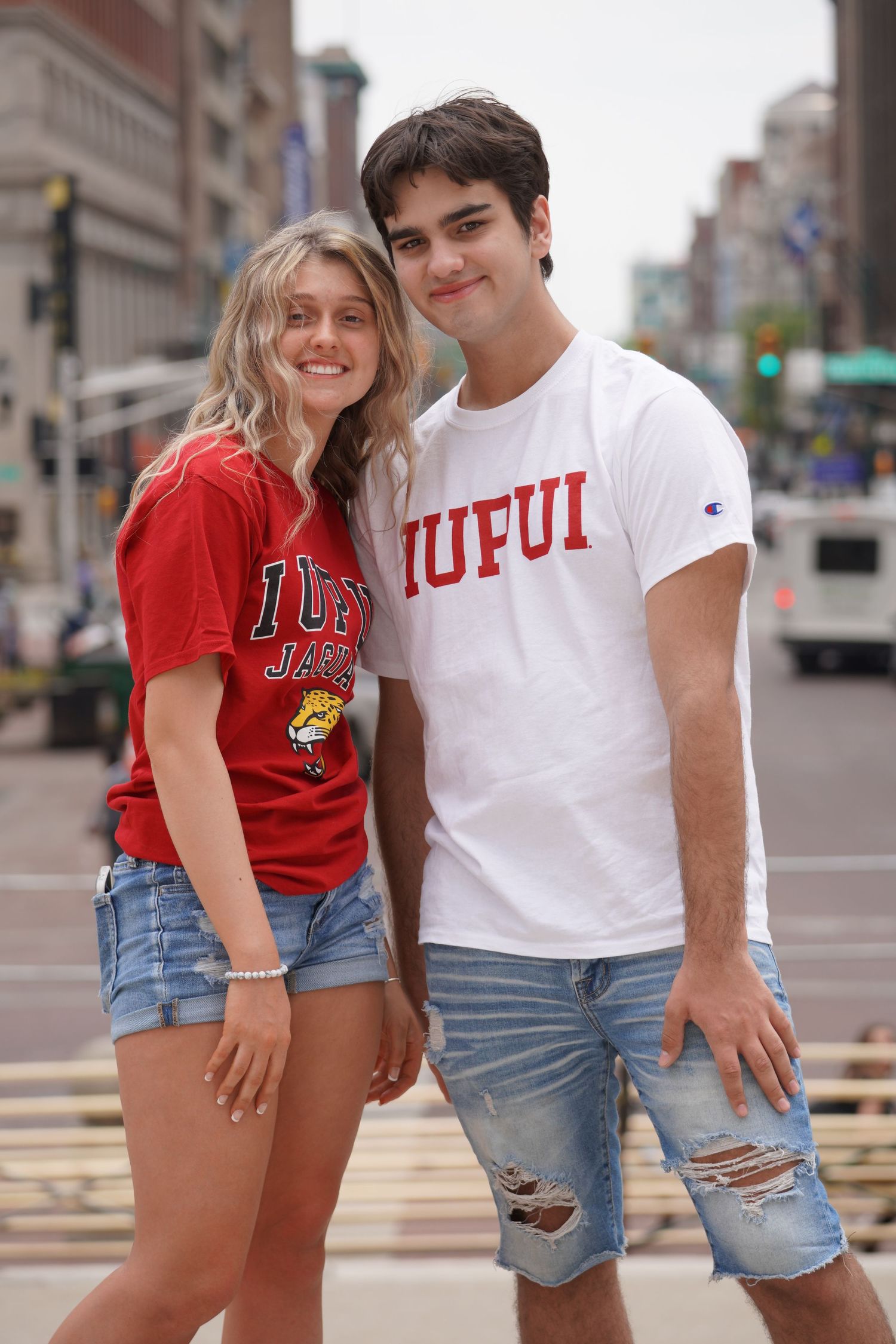 College students wearing IUPUI branded shirts pose on city street.