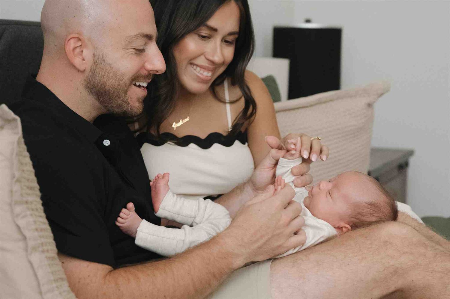 Happy couple sitting on couch sharing tender moment with their newborn baby at home.