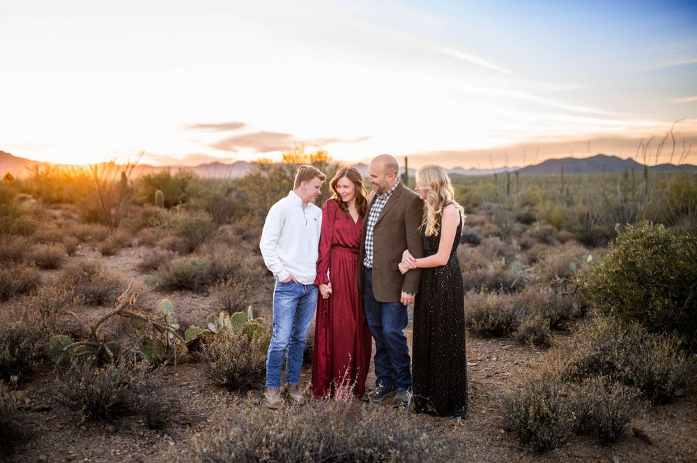 Family of four sharing a warm moment together at golden hour in the Arizona desert with saguaro cacti.