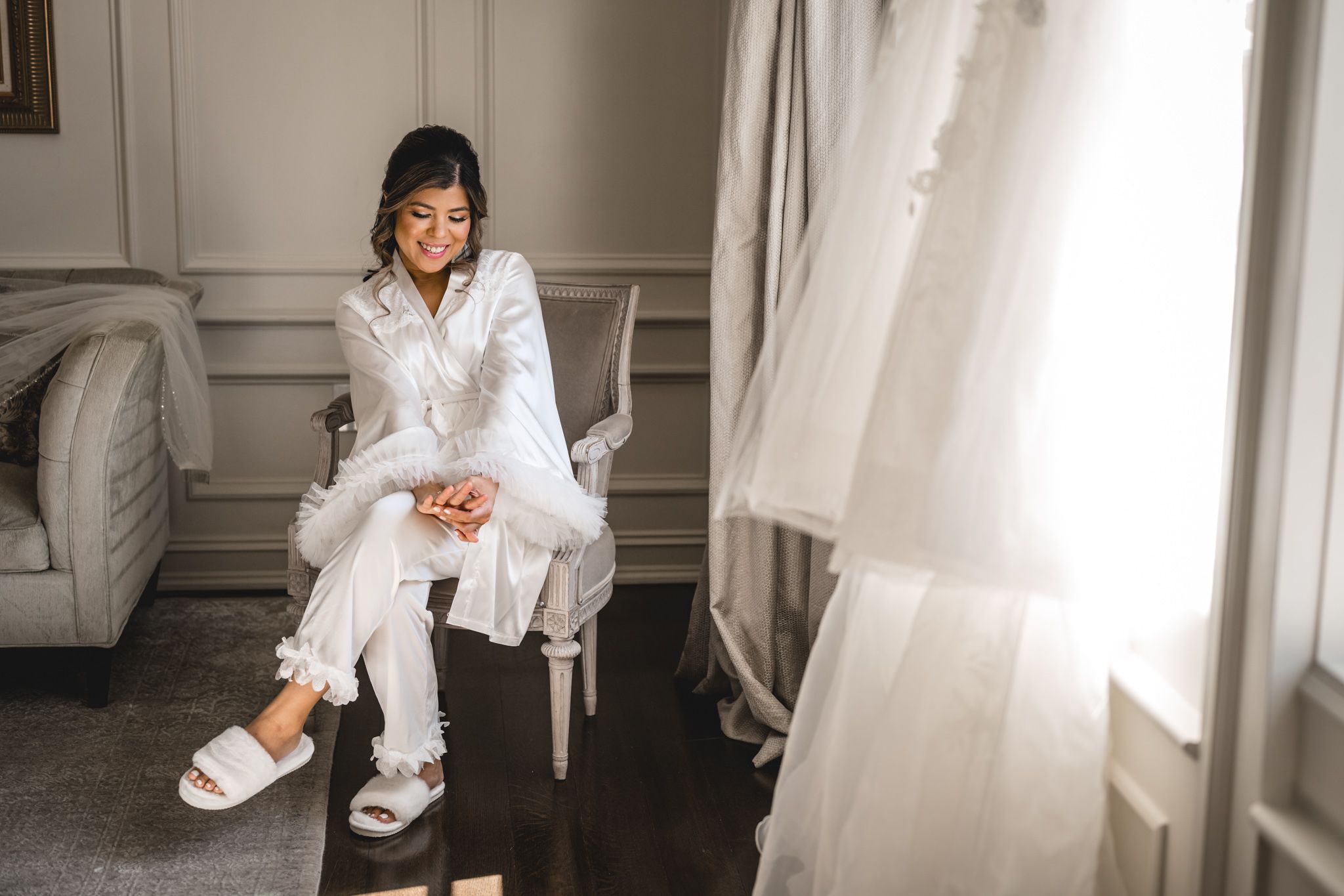 Natural light streams through window during bridal preparation in elegant room.