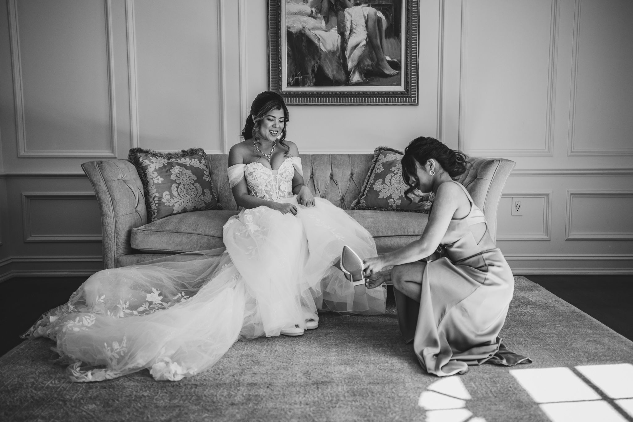 Black and white portrait of bridal preparation in classic interior setting.