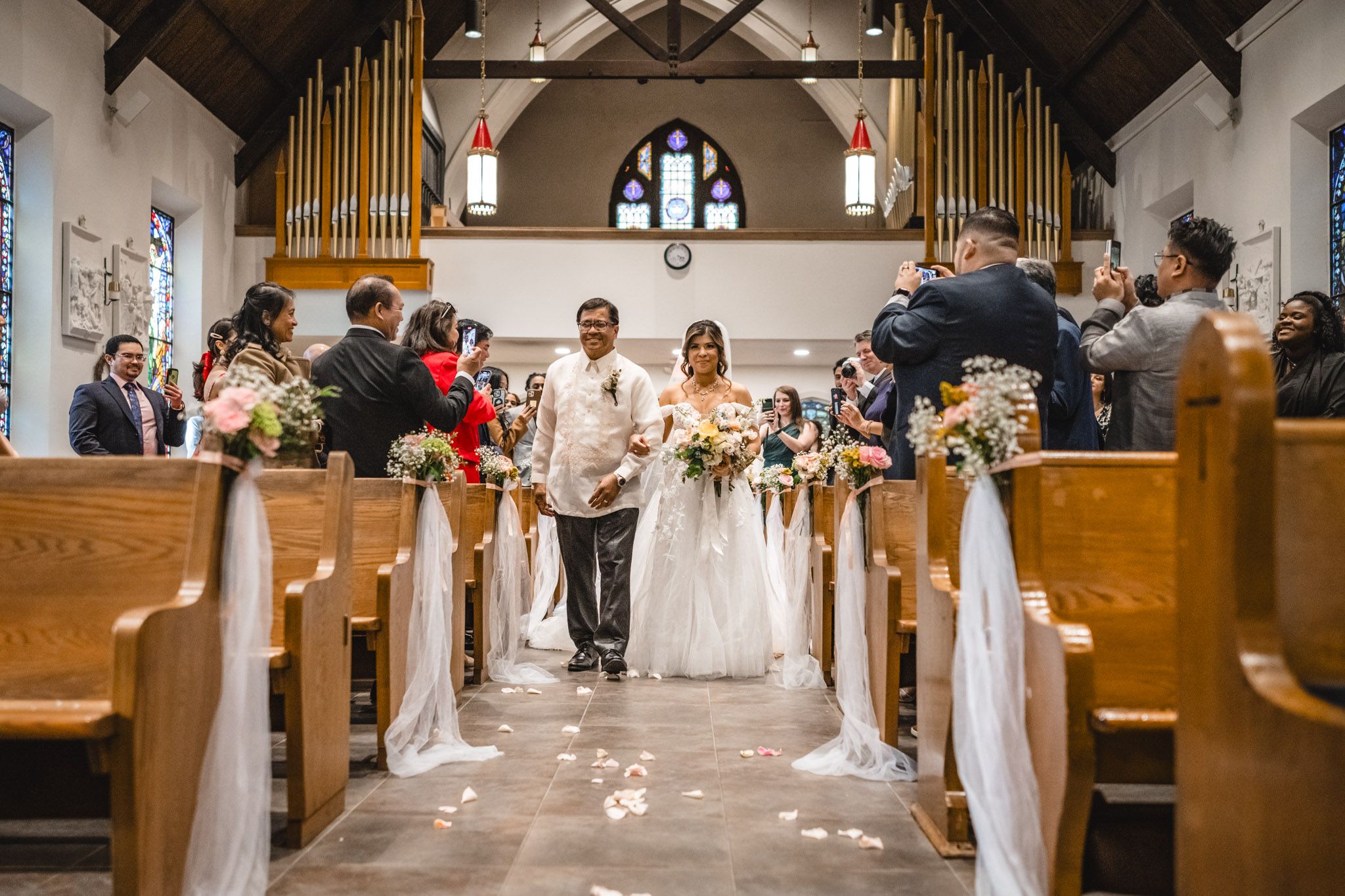 Interior of a church with wooden pews and golden organ pipes during a wedding ceremony.