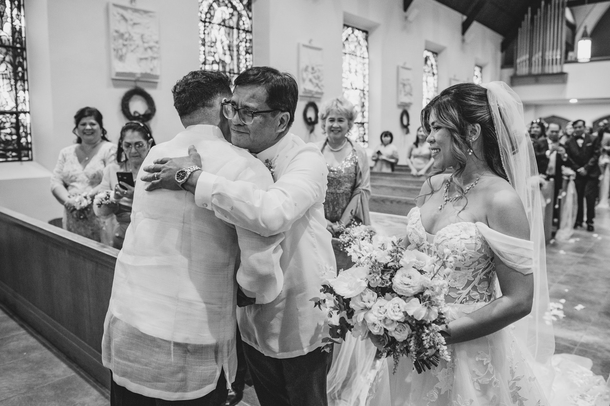 Wedding ceremony processional in a traditional church with guests watching from wooden pews.