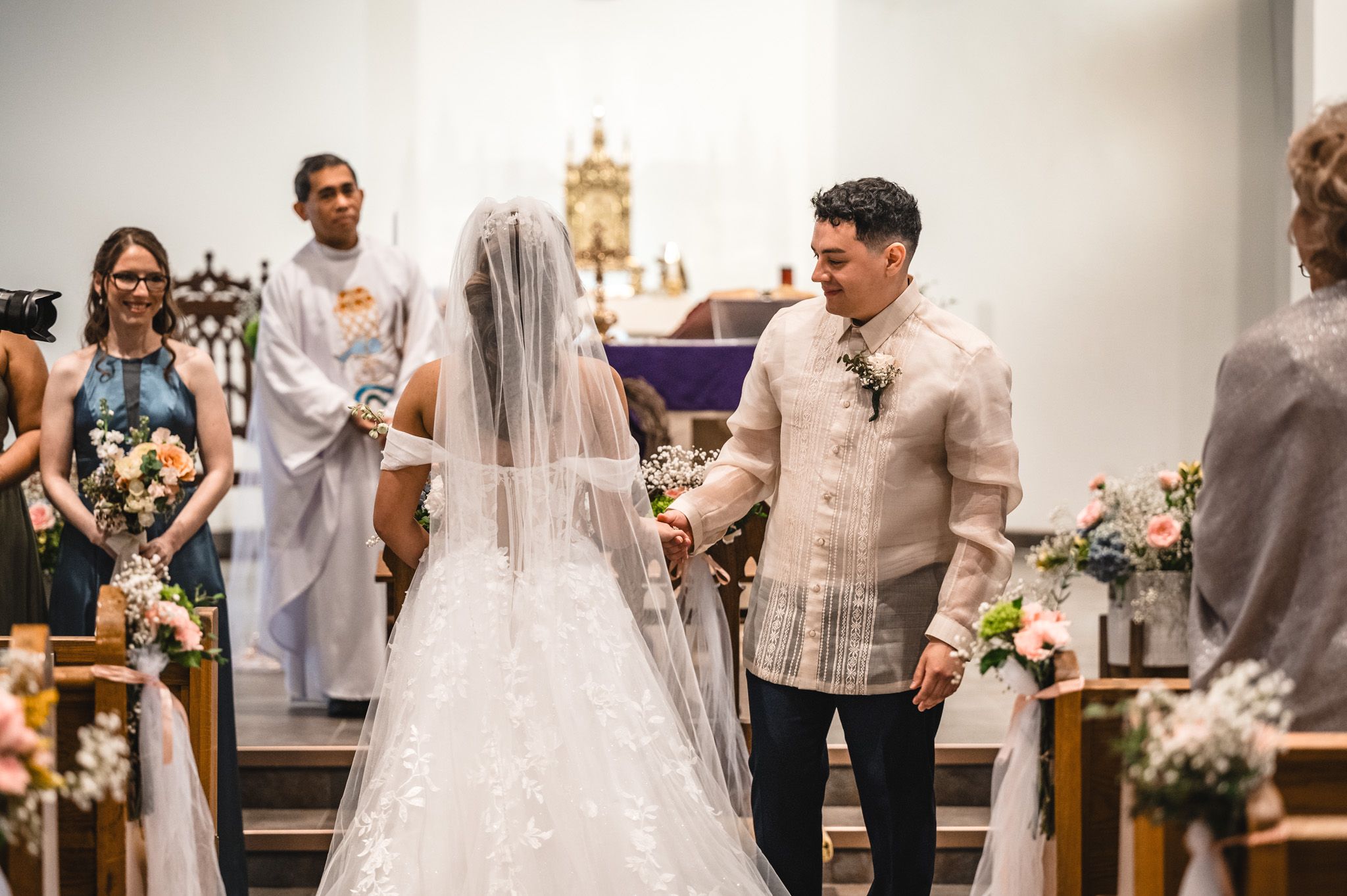 Wedding celebration inside a bright church with traditional Filipino formal attire and decorations.