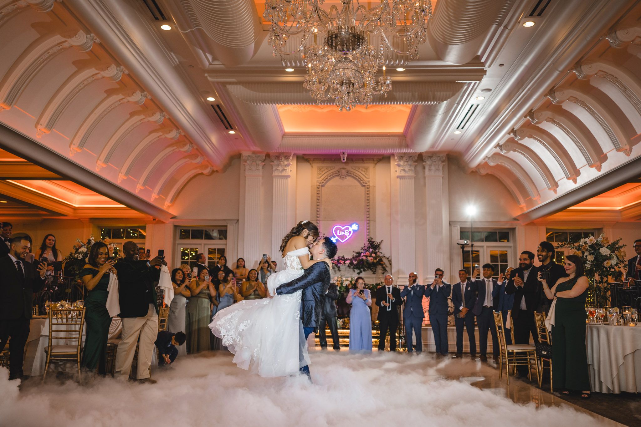 Grand ballroom with crystal chandeliers and vaulted ceilings during wedding reception.