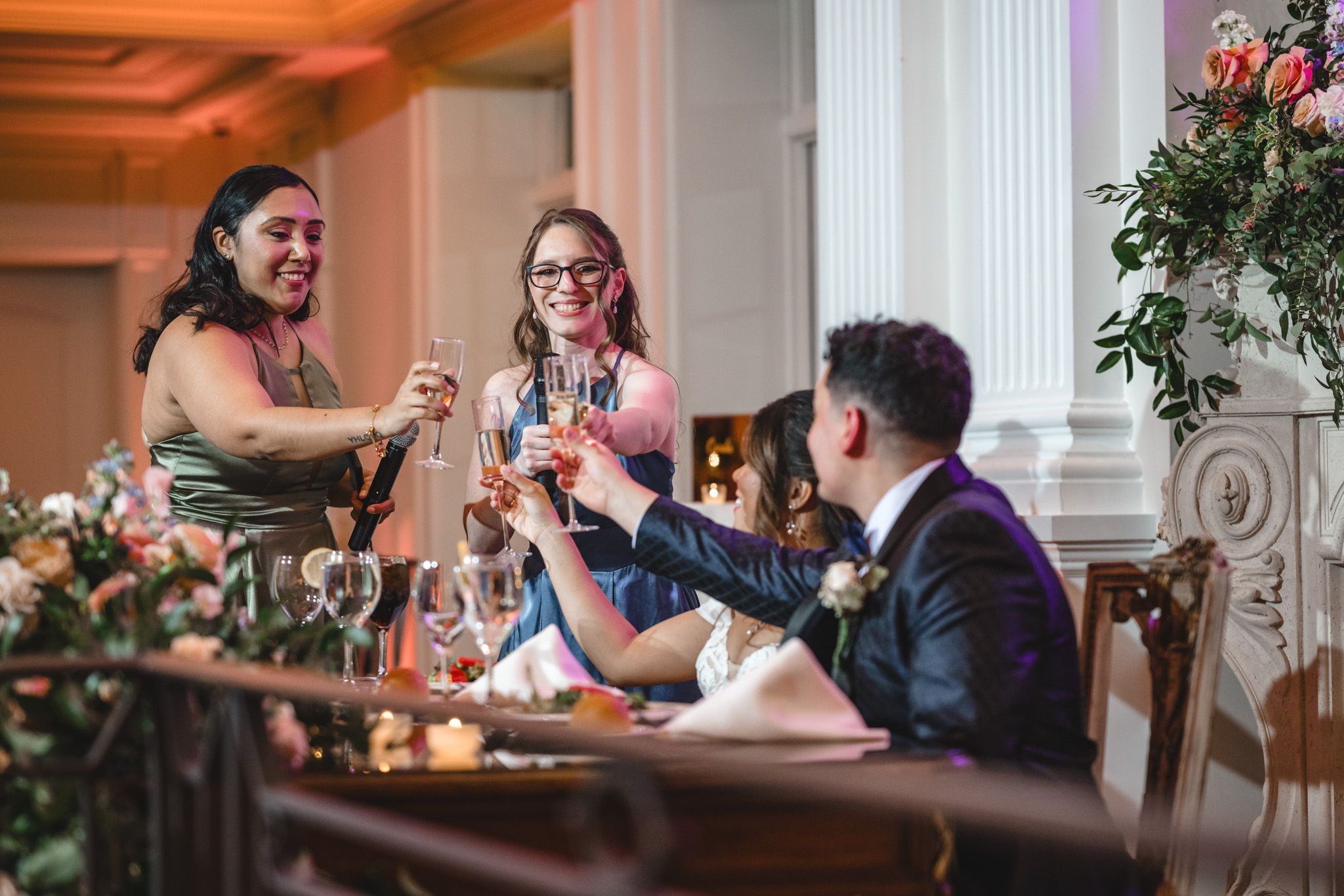Wedding guests raise glasses in celebration during reception toasts.