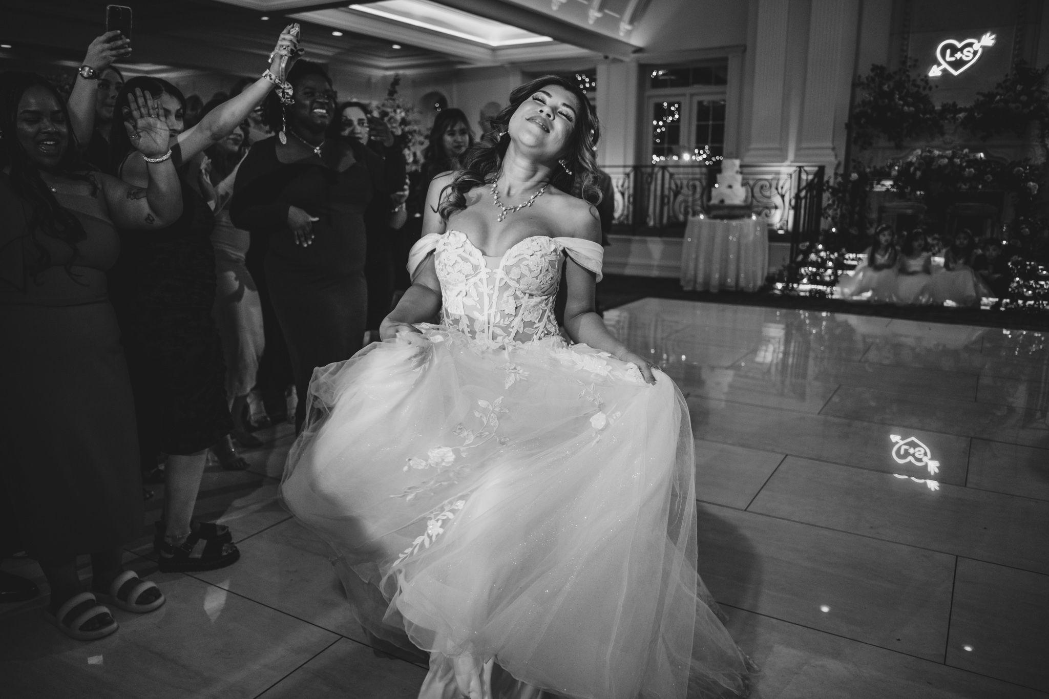 Black and white photo of bride twirling in her flowing wedding dress on the dance floor.