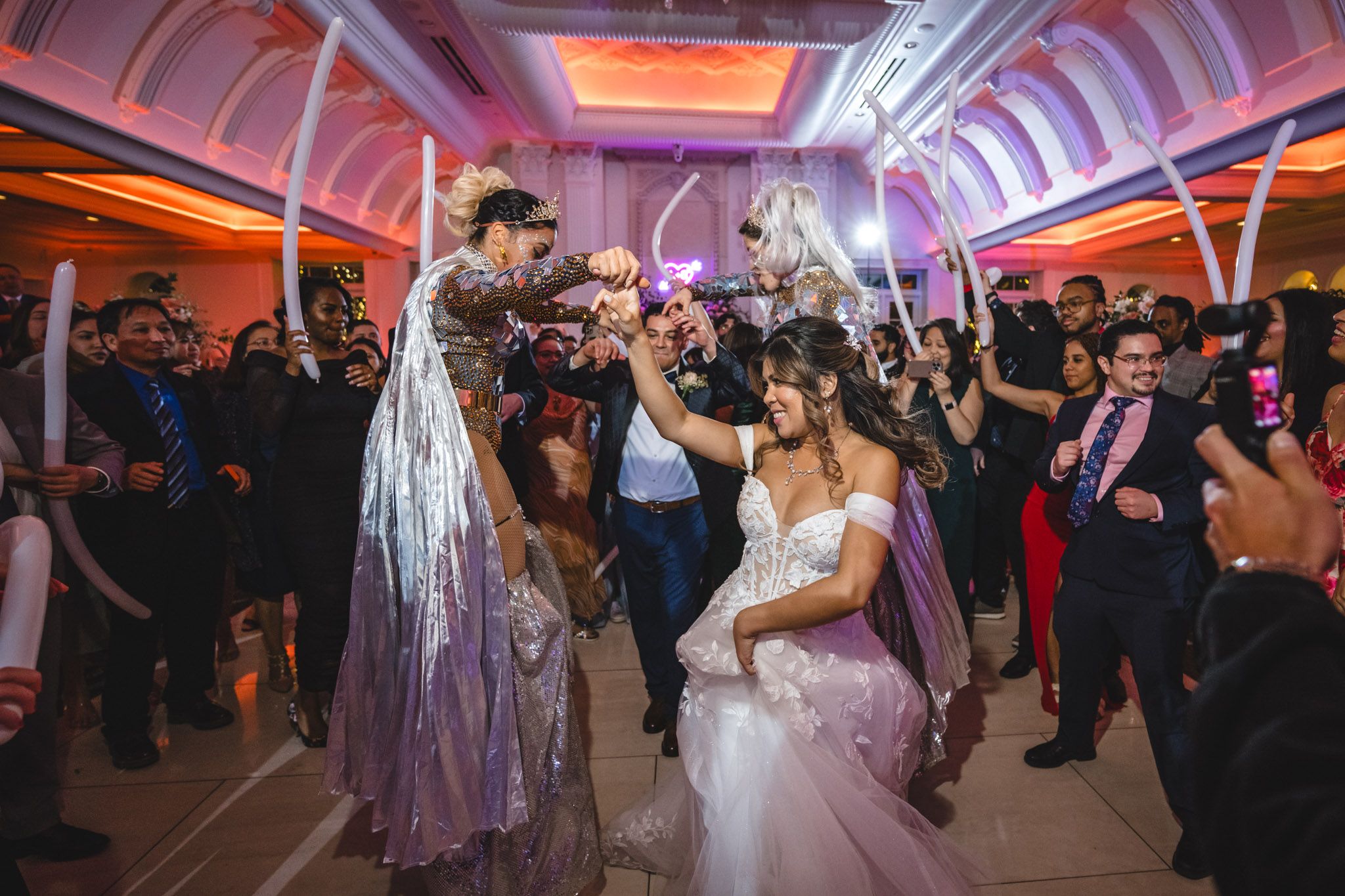 Lively wedding reception dance party with dramatic lighting and celebrating guests.