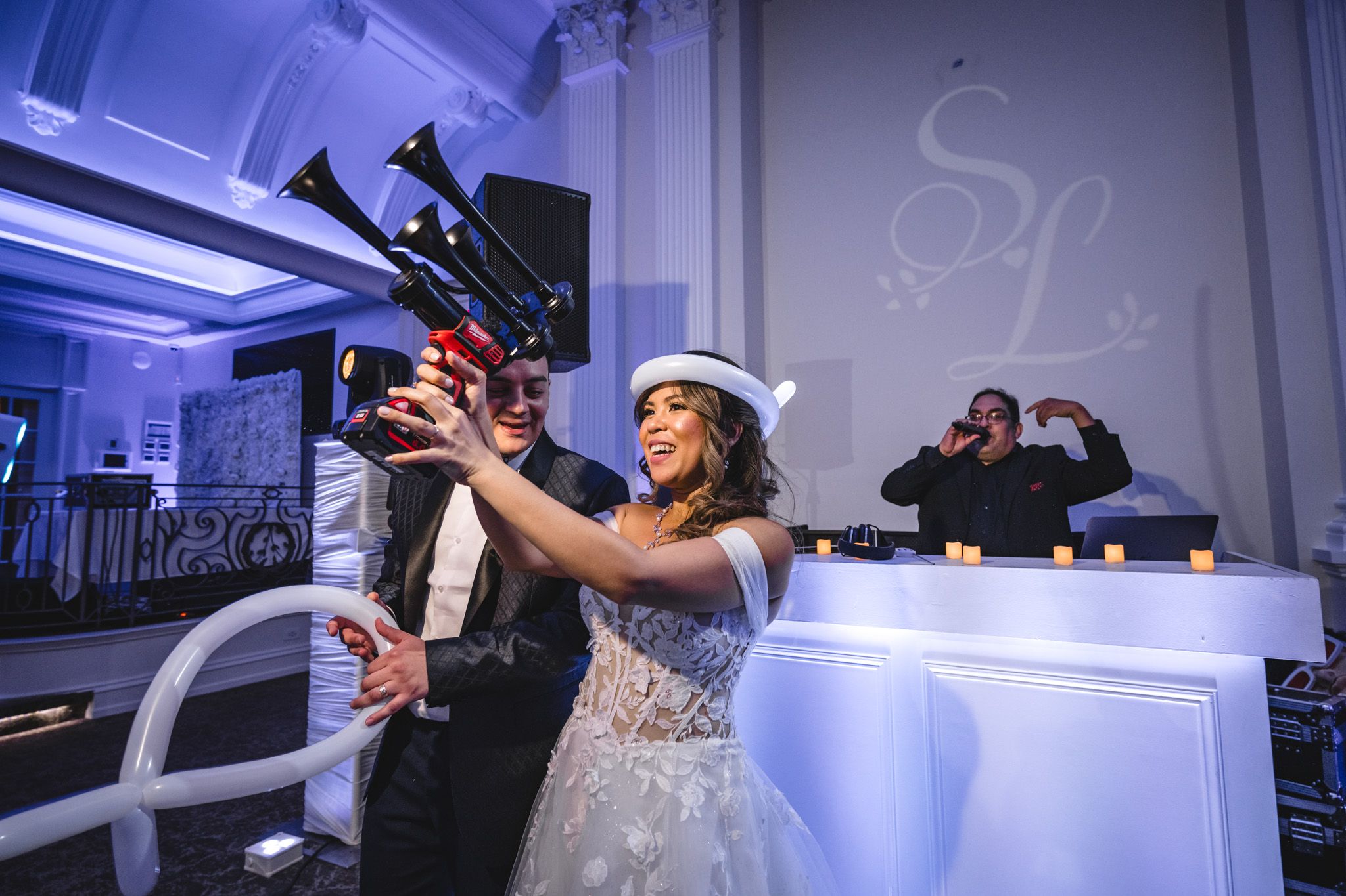 A couple celebrates with champagne at their wedding reception under blue ambient lighting.