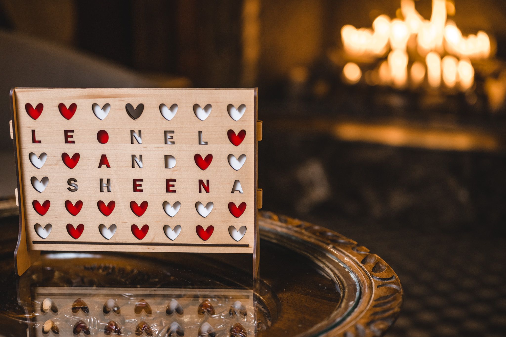 Decorative heart-themed wedding signage displayed in warm candlelight at reception.