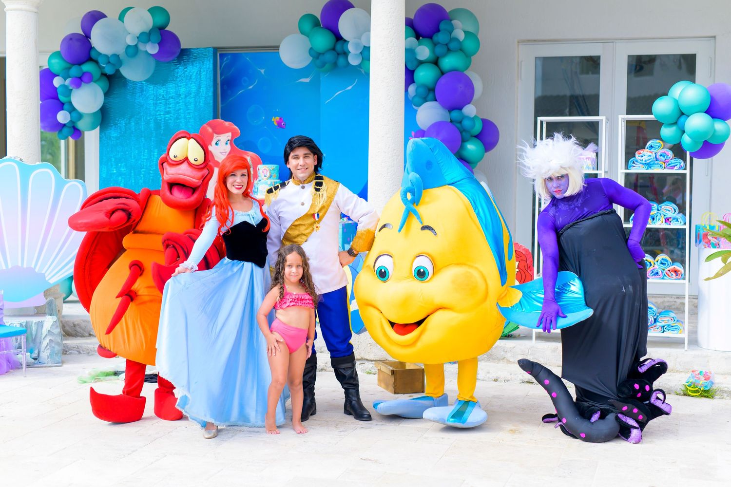 Group photo with costumed characters and balloon decorations at themed party event.