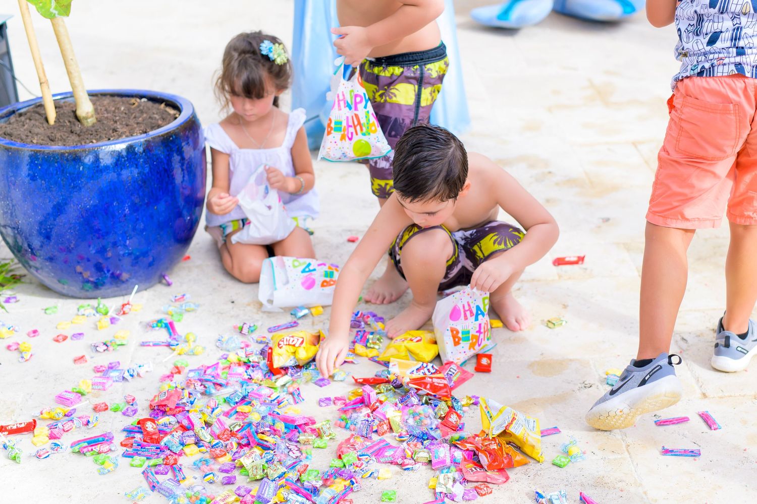 Children collecting candy and treats scattered on ground at party event.