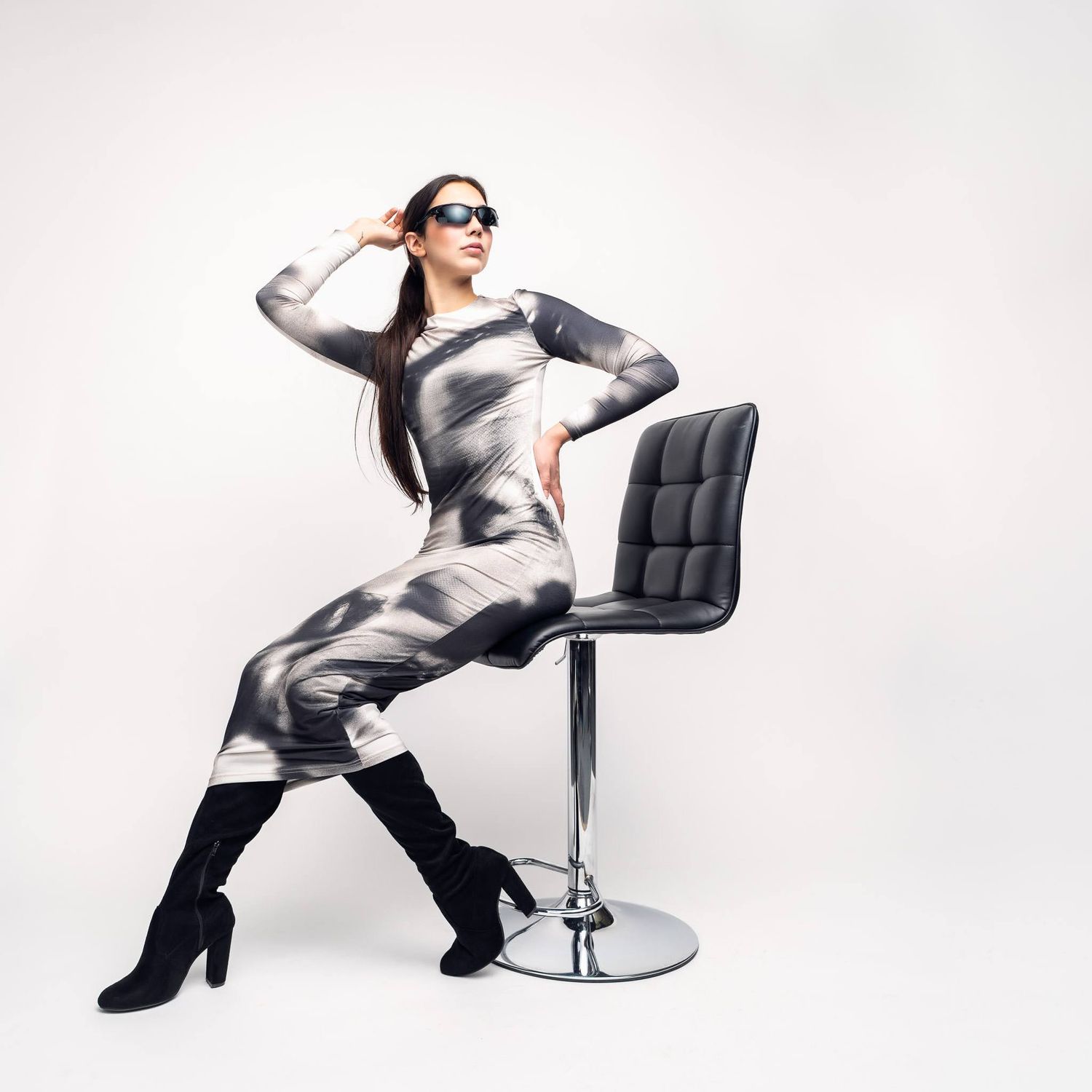 Model in striking zebra print bodysuit poses dramatically with modern black chair.