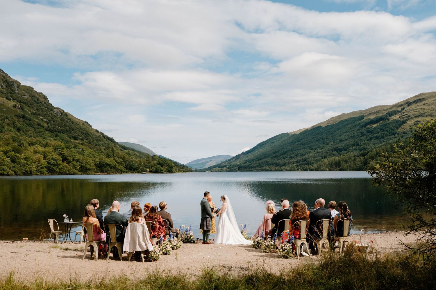 Scenic lakeside wedding ceremony setup with mountains and water in the background.