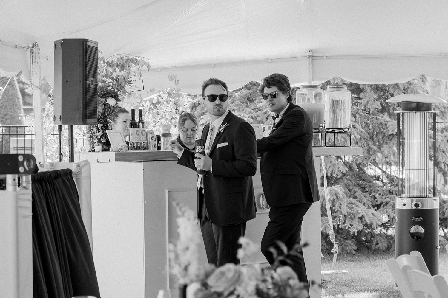 Black and white wedding photo showing formal outdoor celebration under white tent.