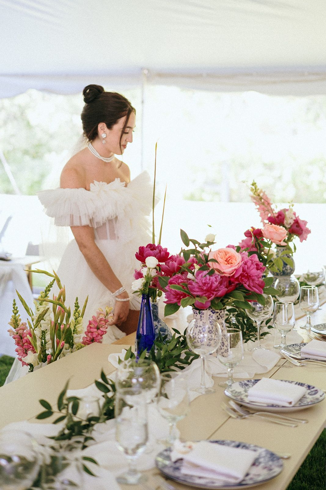 Elegant table settings with blue china plates and vibrant pink floral centerpieces at outdoor reception.