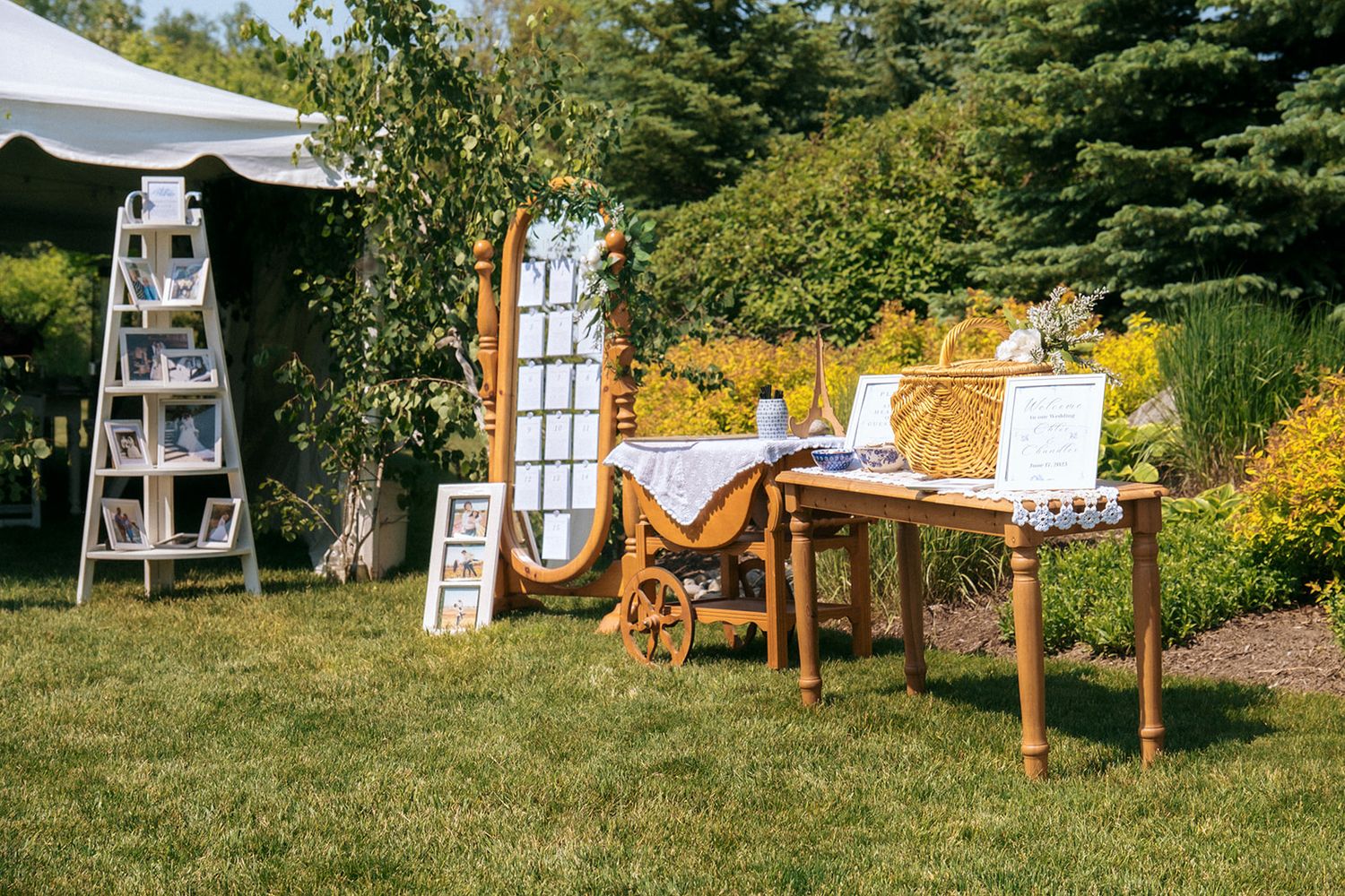 Outdoor wedding decor setup with wooden furniture and display stands in garden setting.
