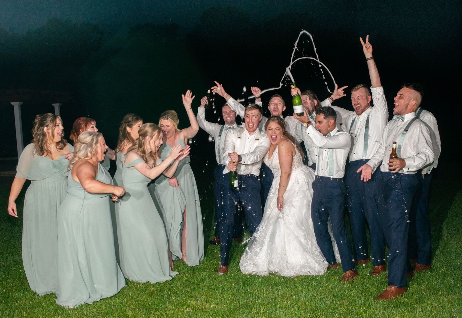 Wedding party celebrating outdoors at night with sparklers creating a festive atmosphere.