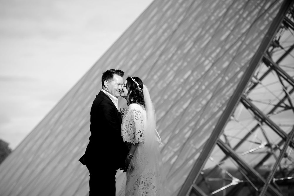 Black and White photo of a bride and groom kissing at the Louvre, captured by Julien LB Photography Paris