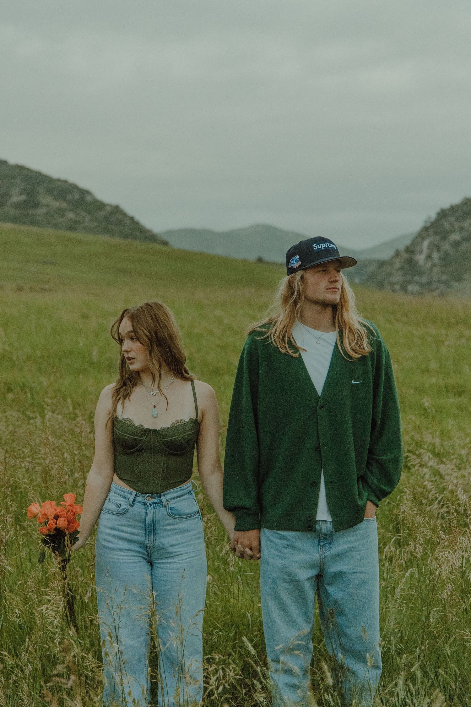 couple holding hands in between them with mountains in the background