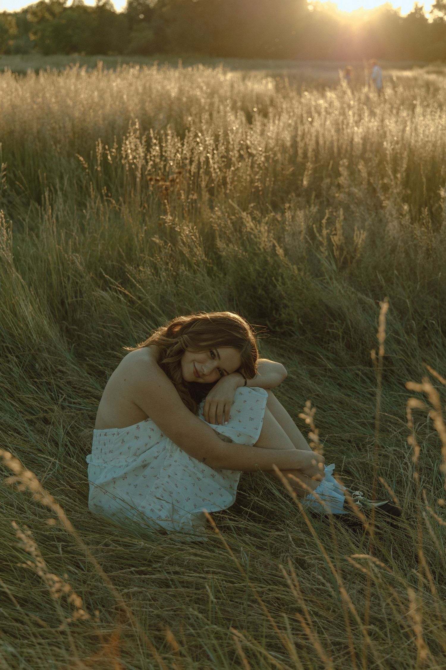 girl in a white dress sitting in a grass field posing in a ball