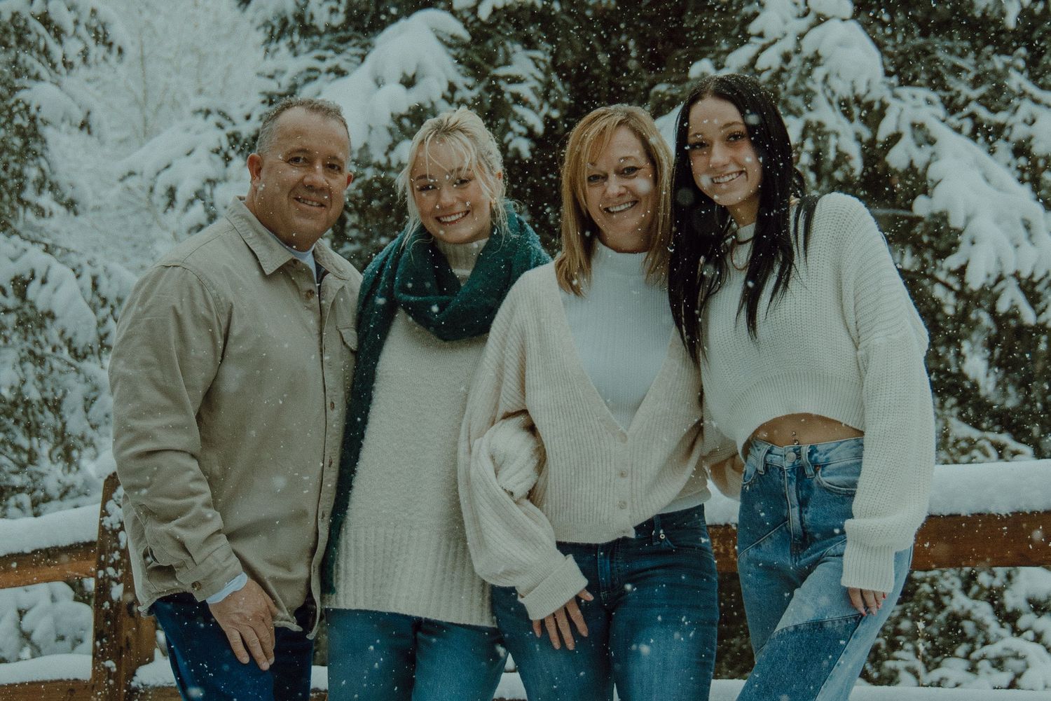 family photo with a mom, dad, and two daughters in the snow