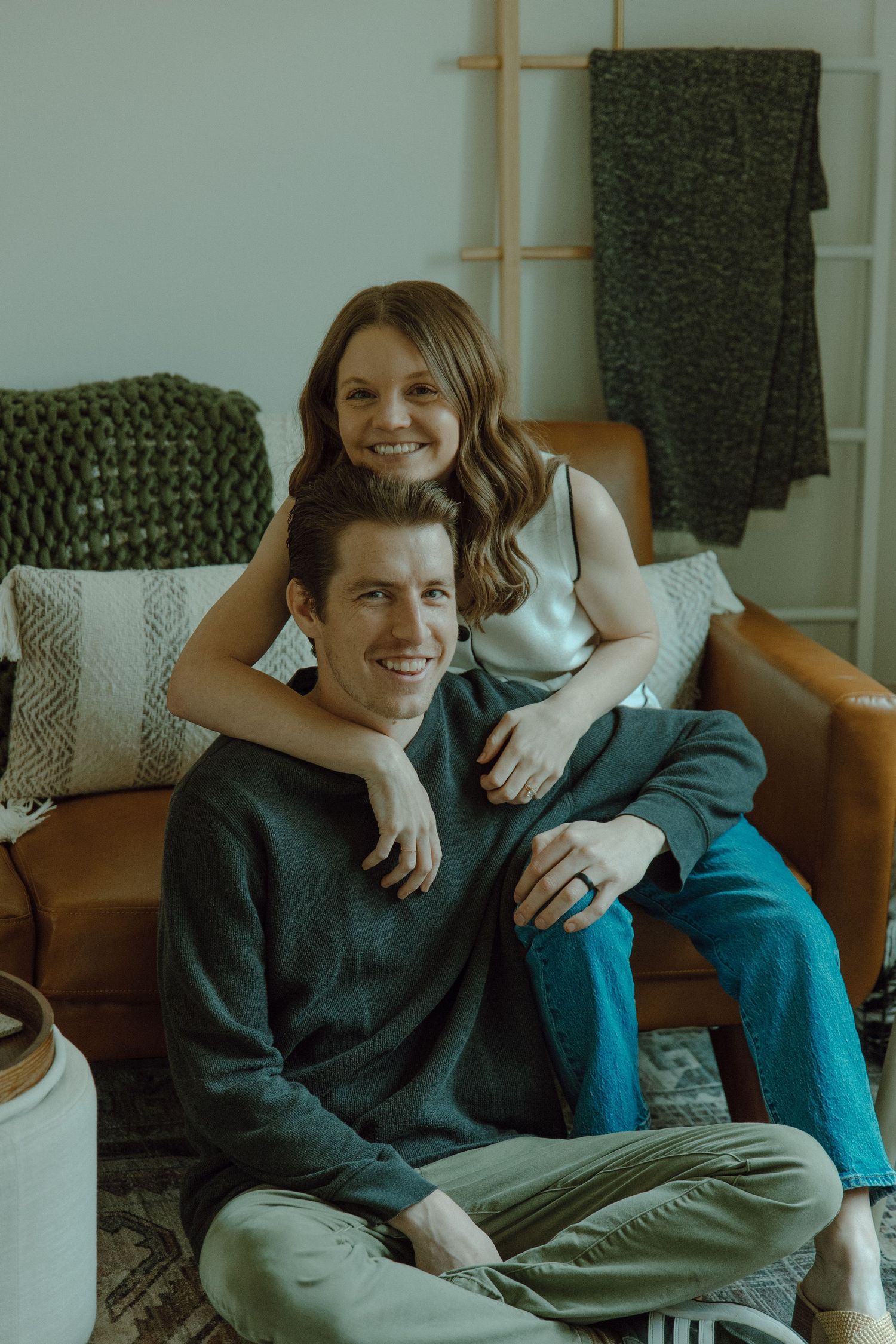Couple sitting together while wife hugs her husband from behind