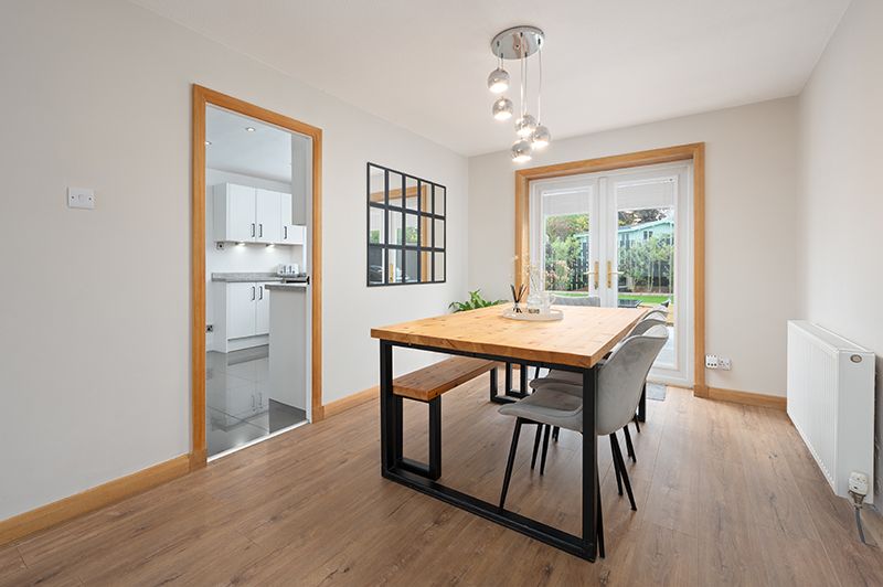 Modern open concept home interior with light hardwood floors, white walls, and natural lighting through multiple windows.