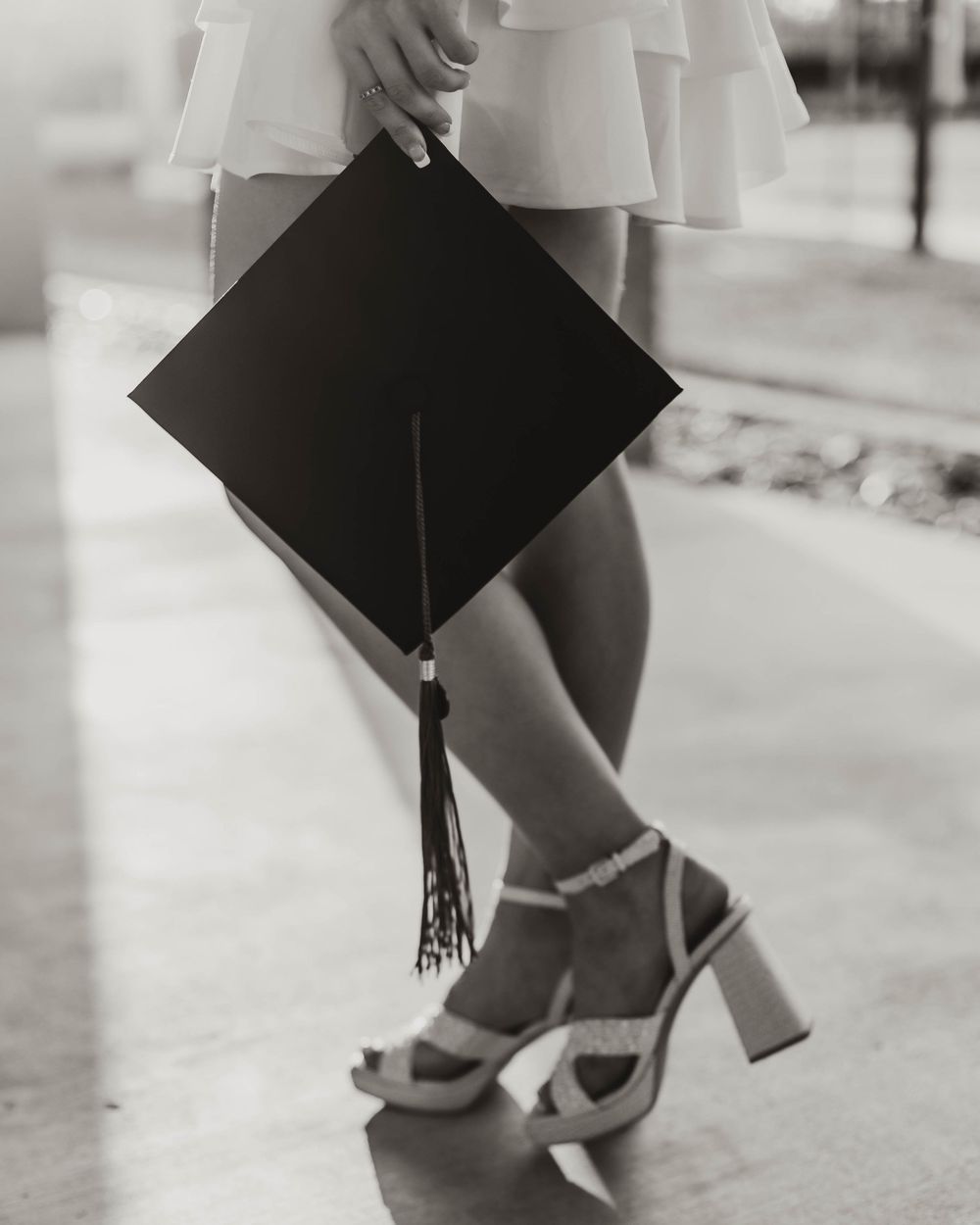 Close-up of graduation cap and heels during celebratory photoshoot.