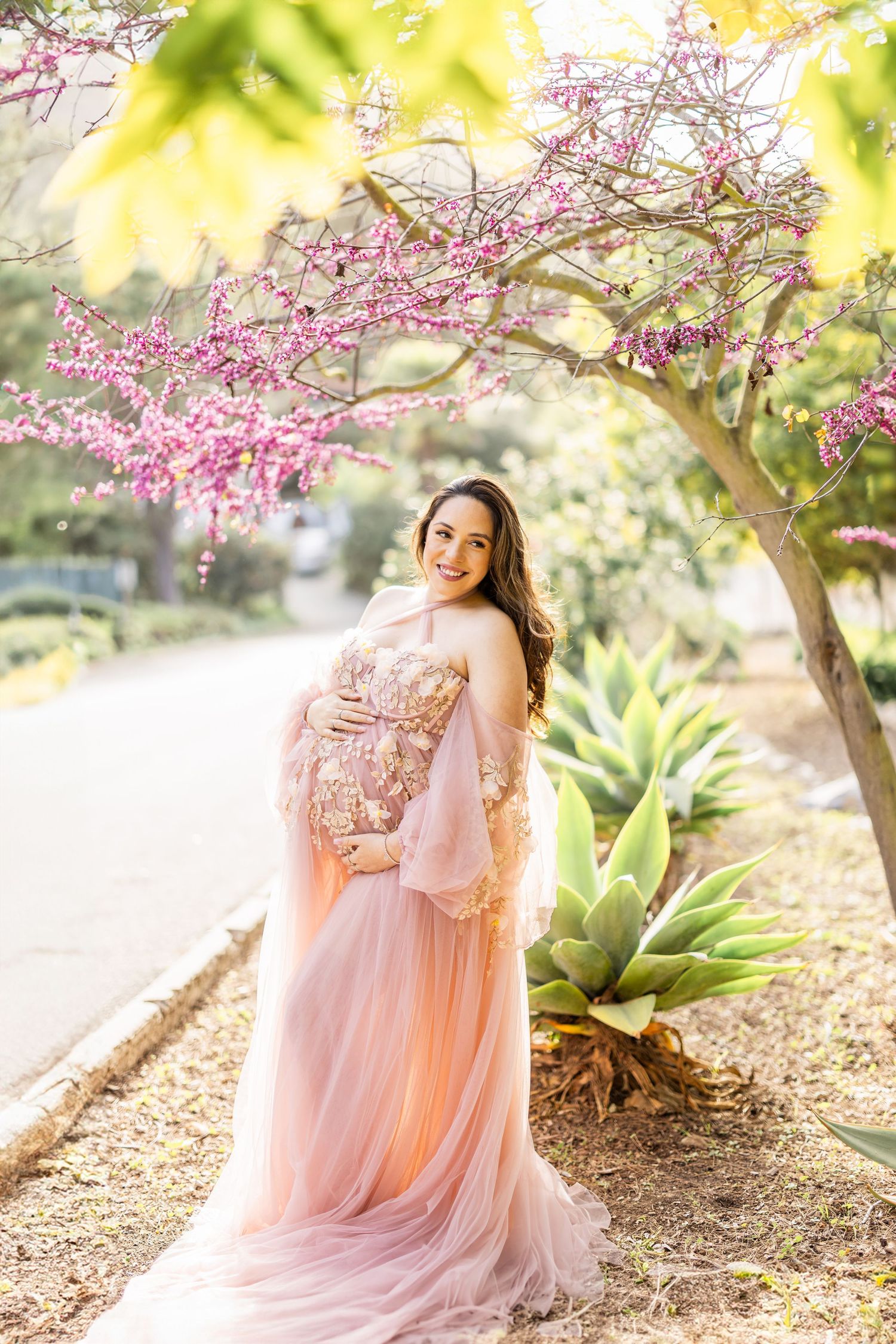 Dreamy maternity portrait with woman in pink dress surrounded by delicate baby's breath flowers.