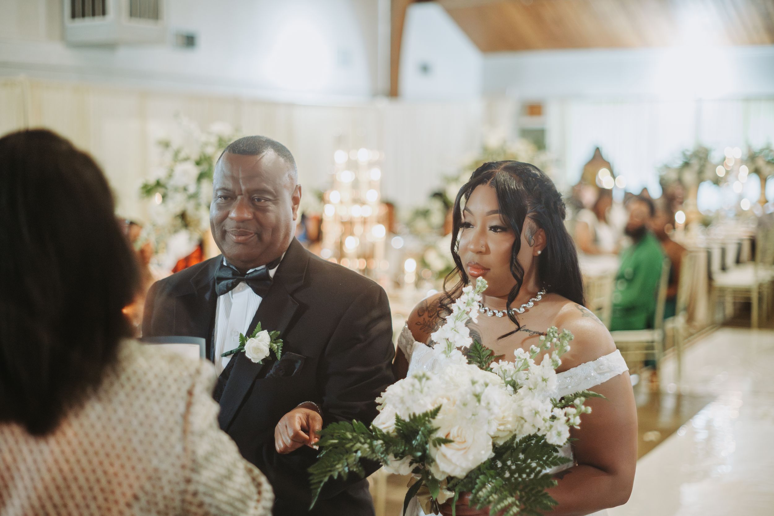 Wedding guests celebrate together during an intimate reception dinner with white floral decor and candlelight.