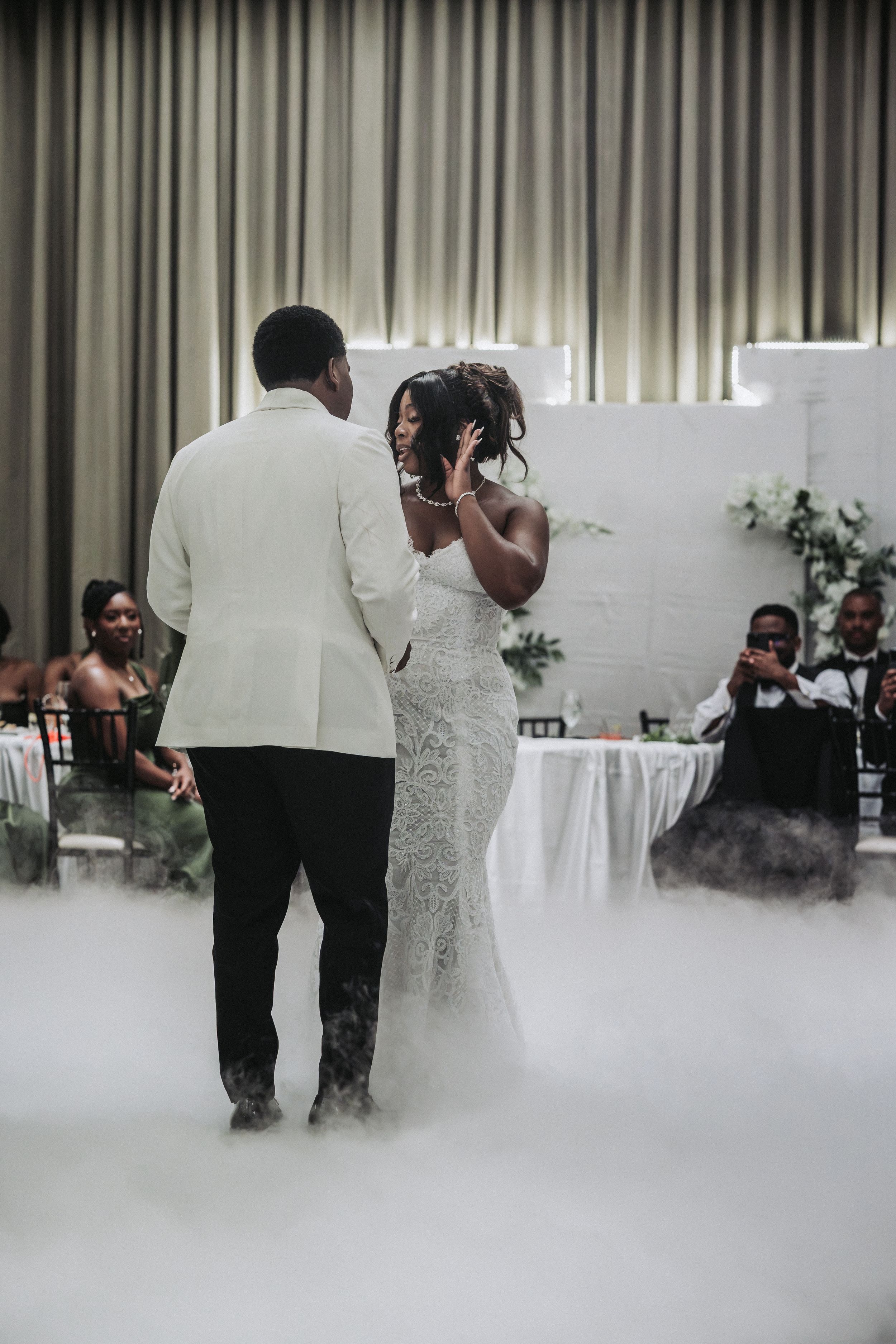 Bride and groom share their first dance surrounded by dramatic fog at an elegant wedding reception.