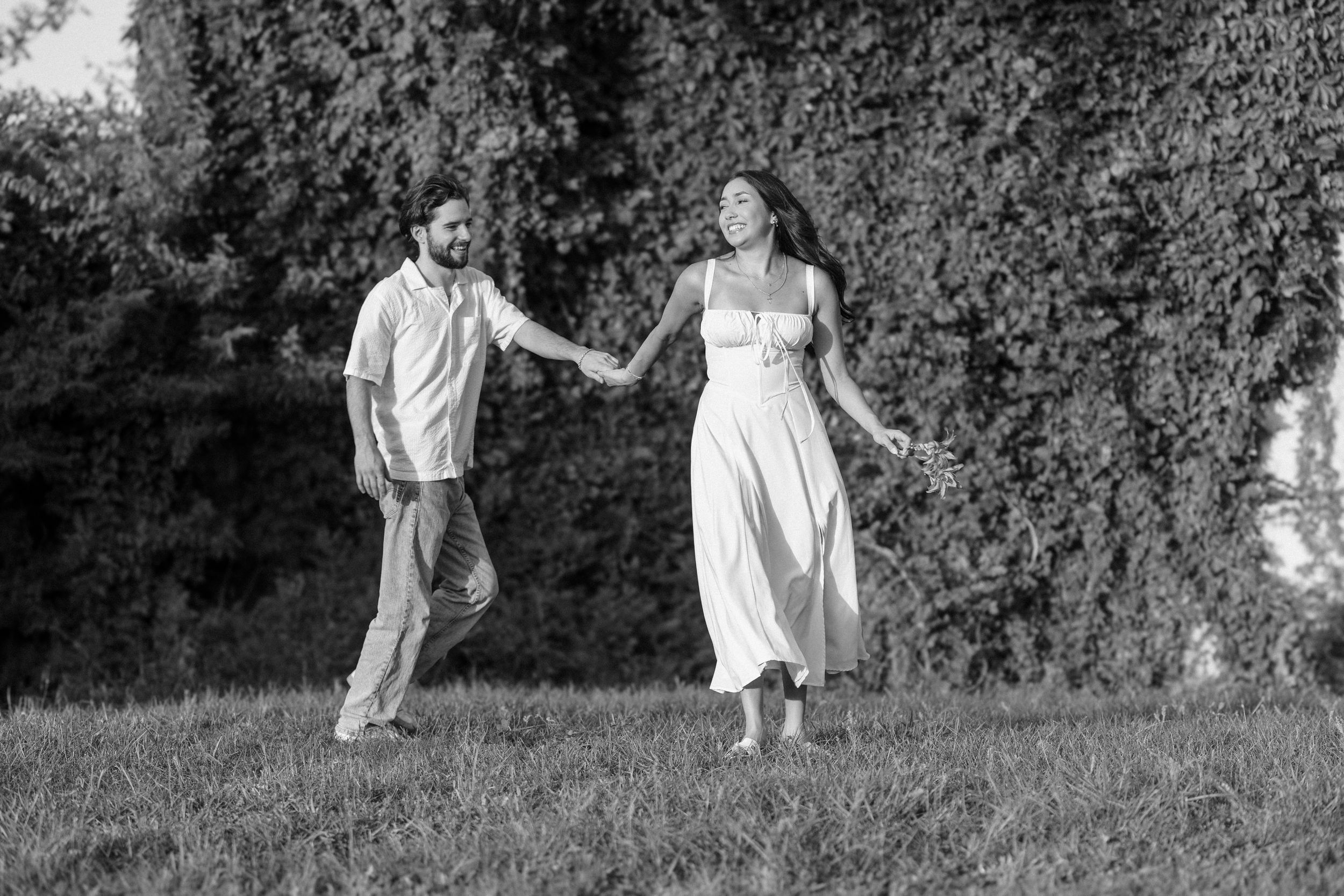 A couple embraces in a garden, sharing a delightful romantic moment filled with laughter.