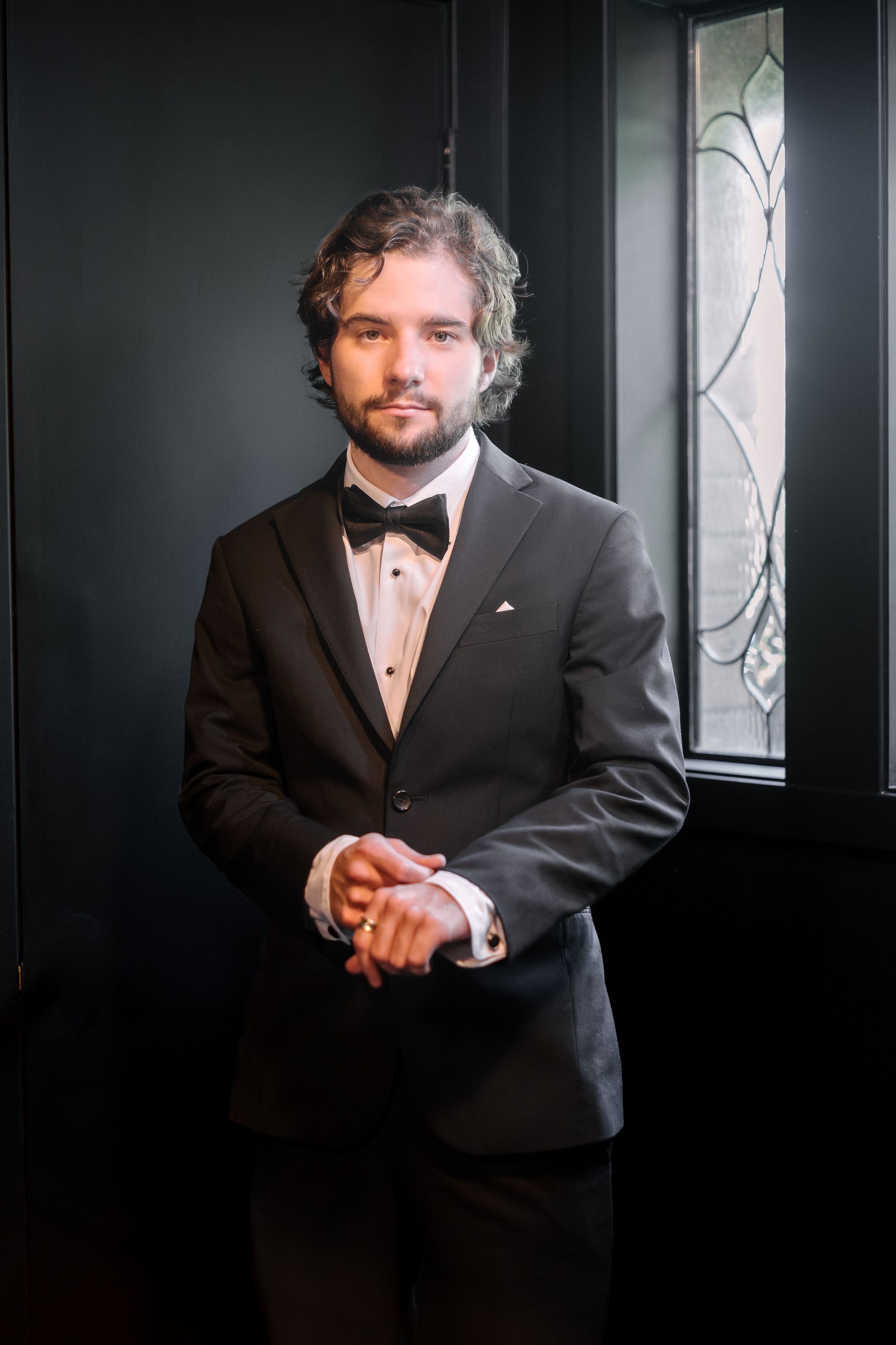 A five-panel sequence of moody portraits in formal black attire against a dark background with dramatic lighting.