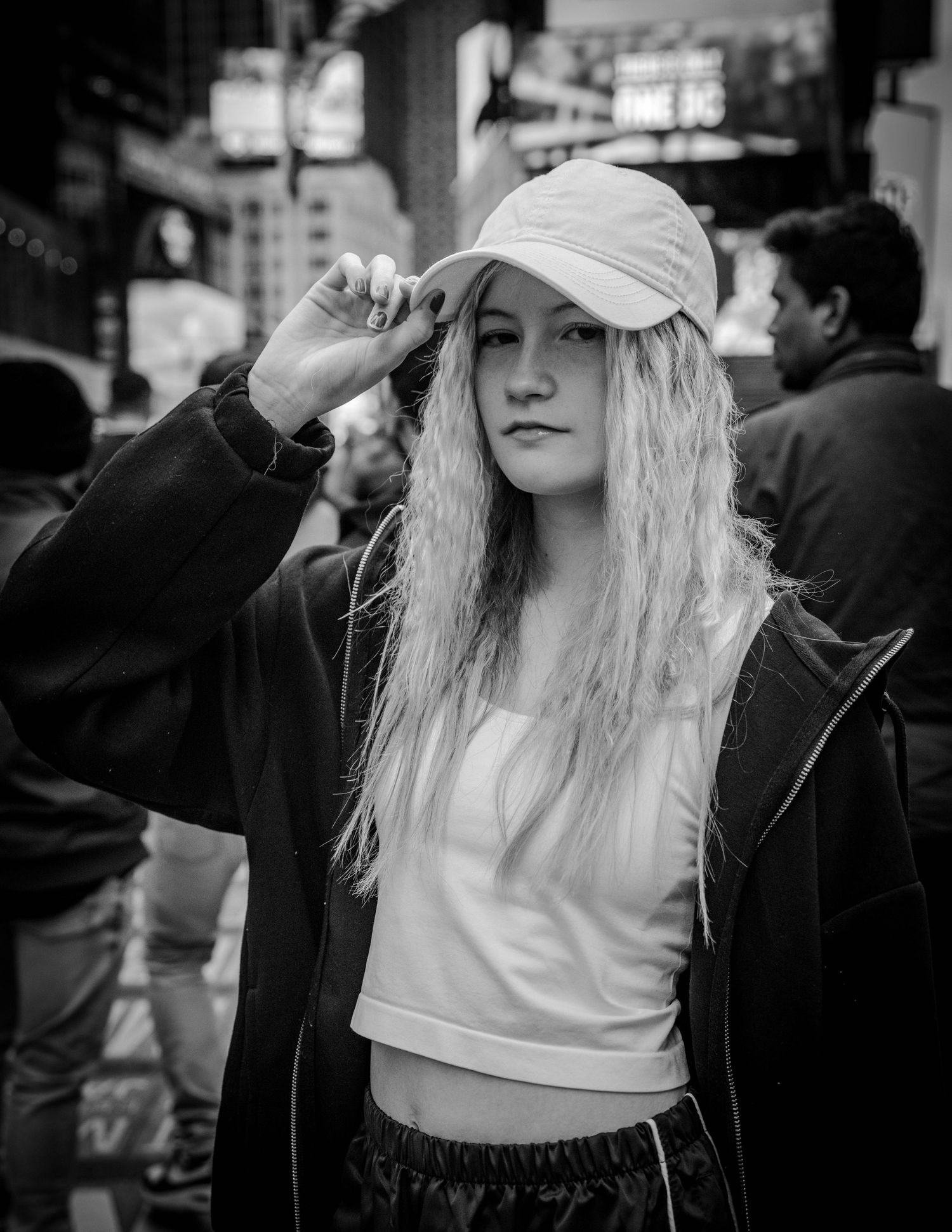 Street style portrait of person in baseball cap and casual wear against urban backdrop.