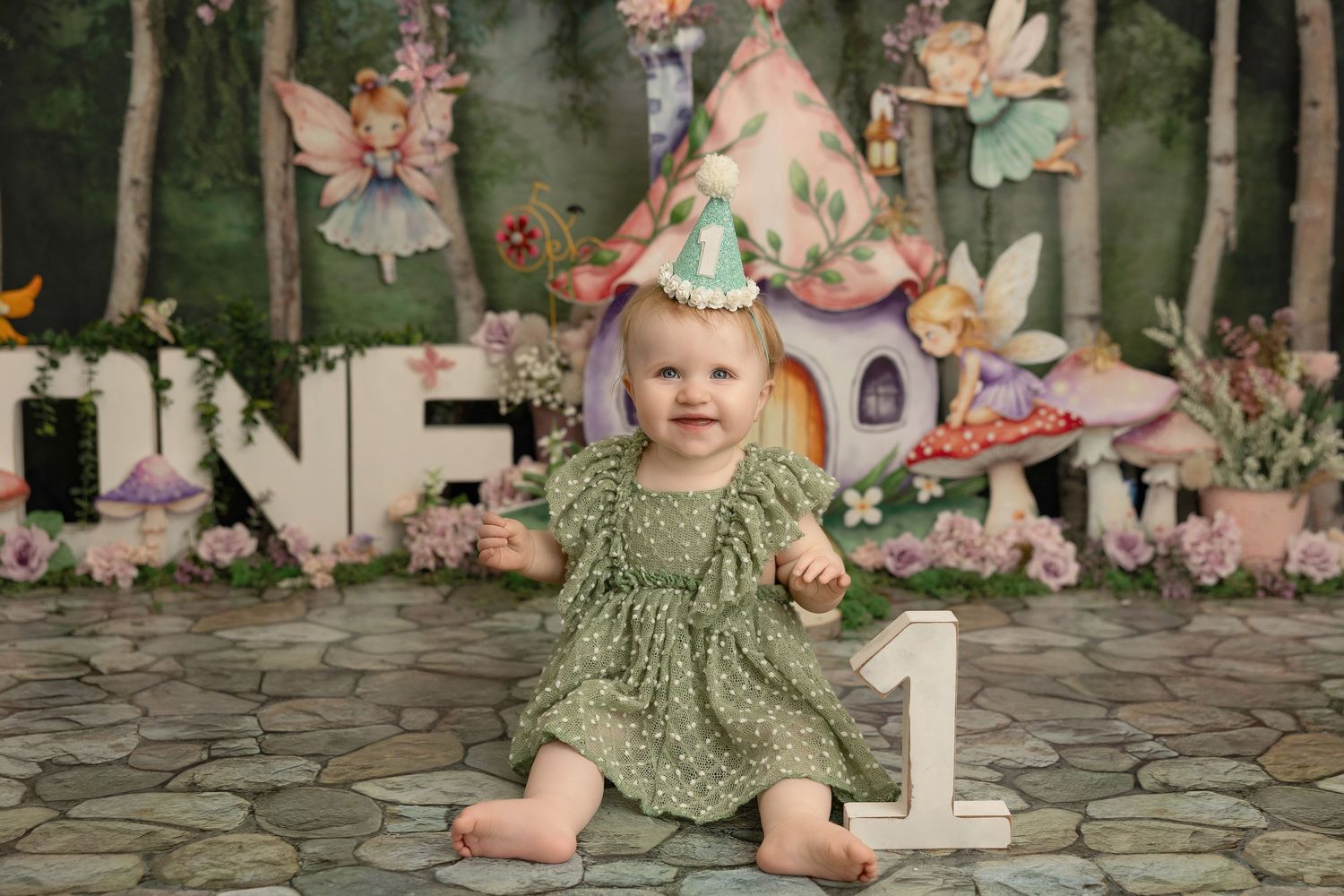 First birthday celebration set up with floral decorations, party hats, and cobblestone patio in whimsical garden theme.