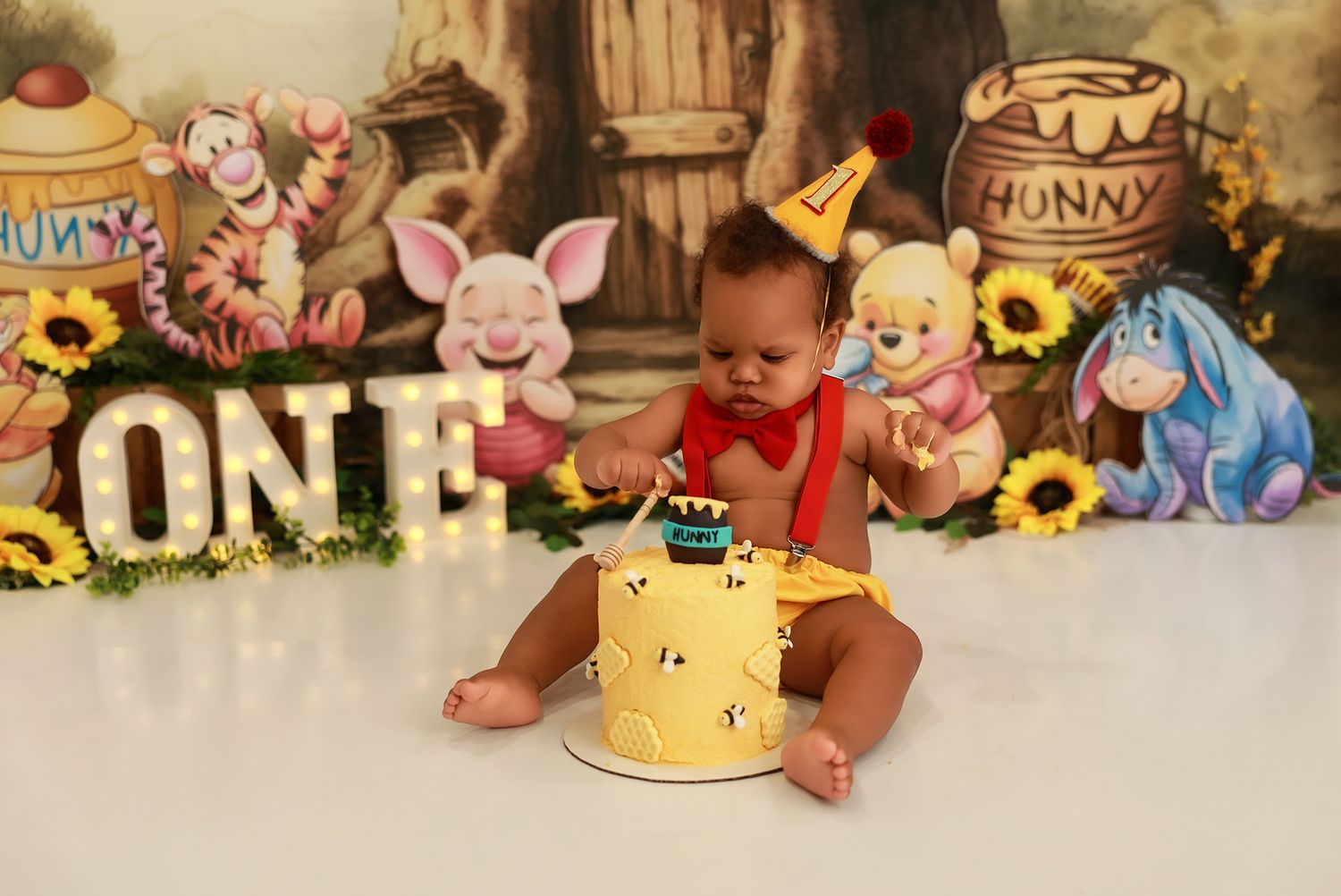 Winnie the Pooh themed first birthday photo session with decorative honey pots and sunflowers in rustic setting.