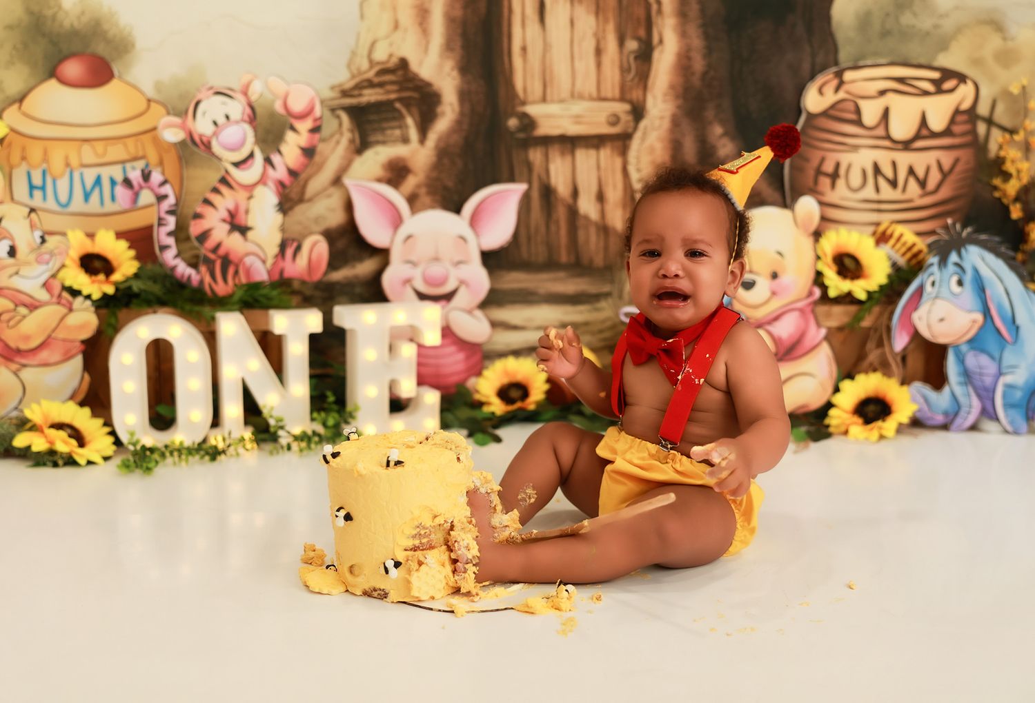 A series of connected photos showing a baby's first birthday cake smash session with Winnie the Pooh themed decorations.