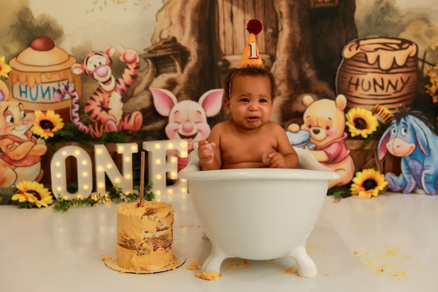 A collection of honey and Winnie the Pooh themed first birthday party decorations arranged in a festive display.