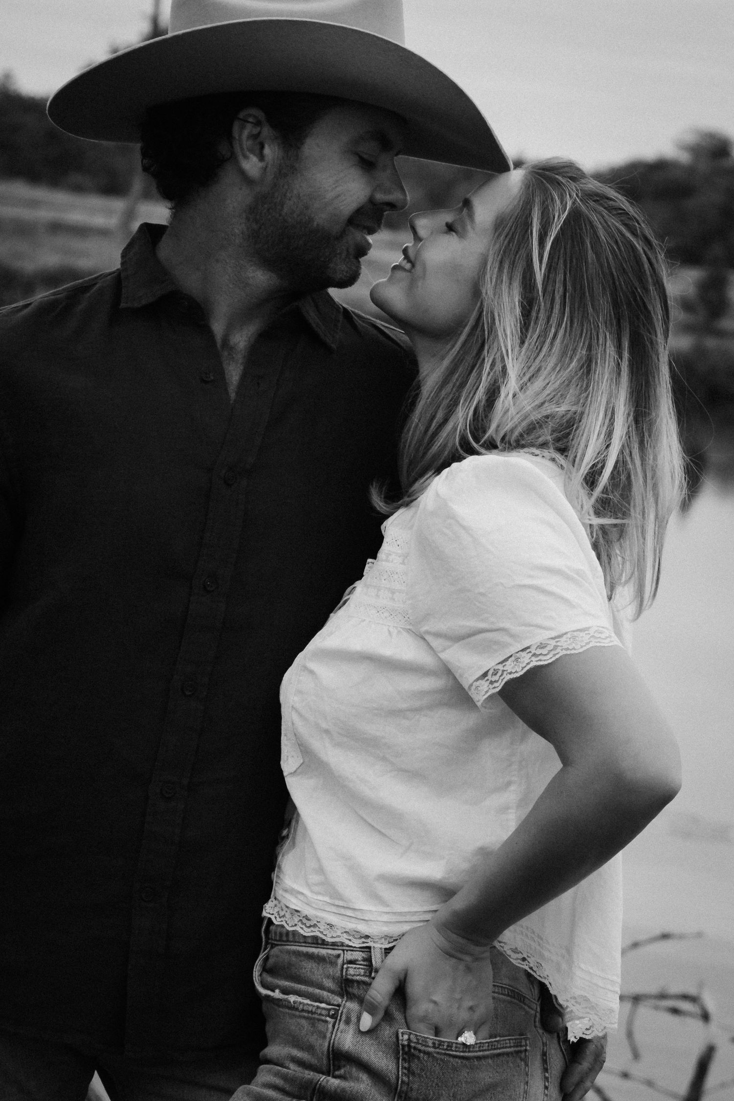 A couple shares an intimate moment on a white porch with coastal architecture in the background.