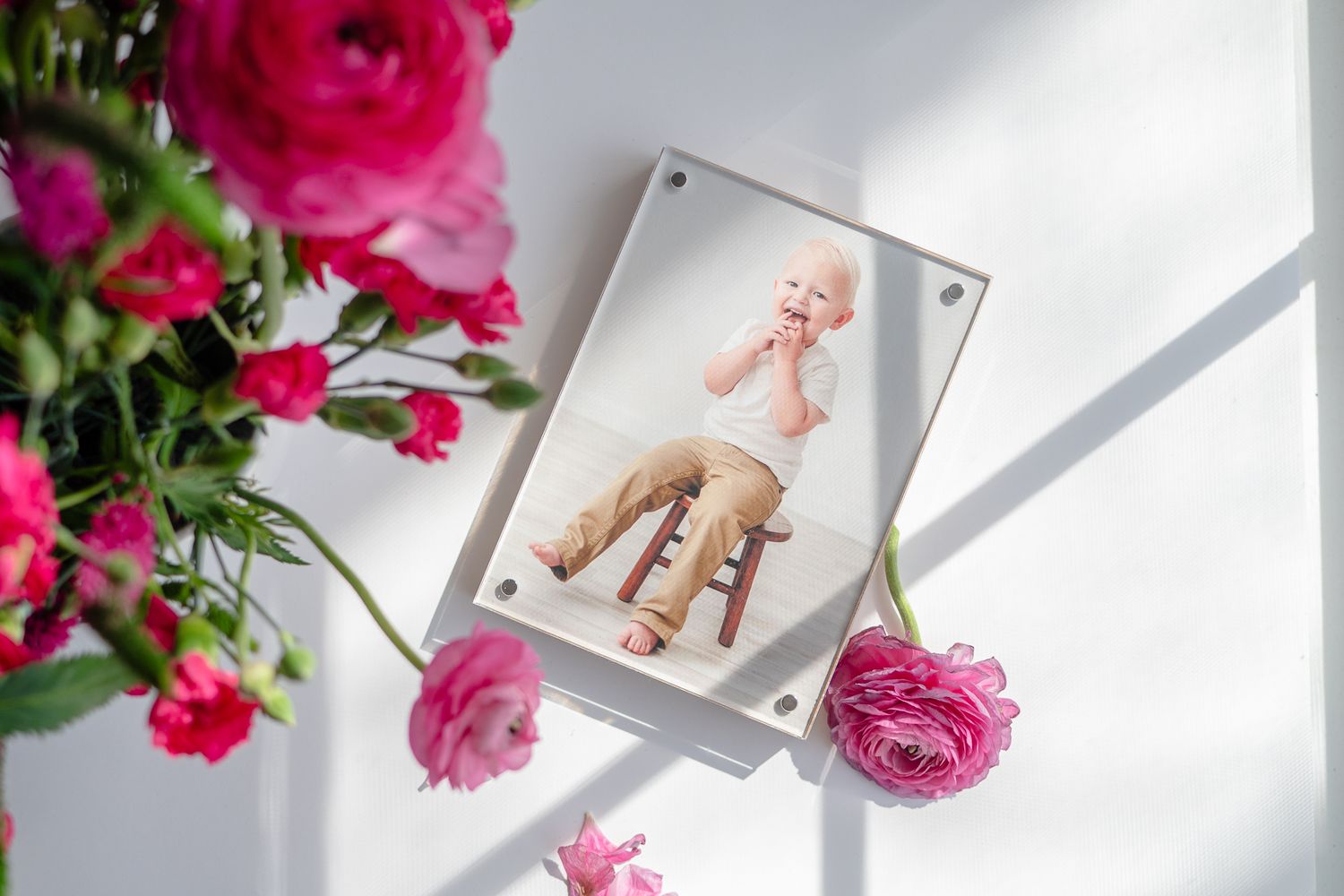 Ballet pointe shoes captured on phone screen with pink roses framing the artistic composition on white surface.