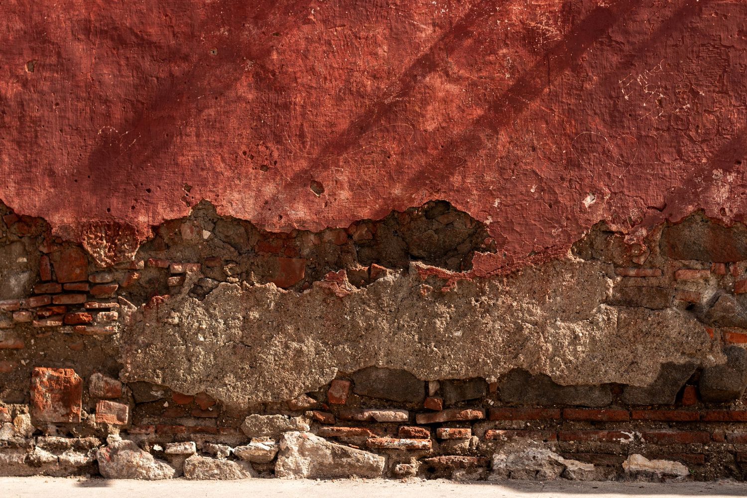 Textured red wall surface showing layers of worn paint and aging effects.