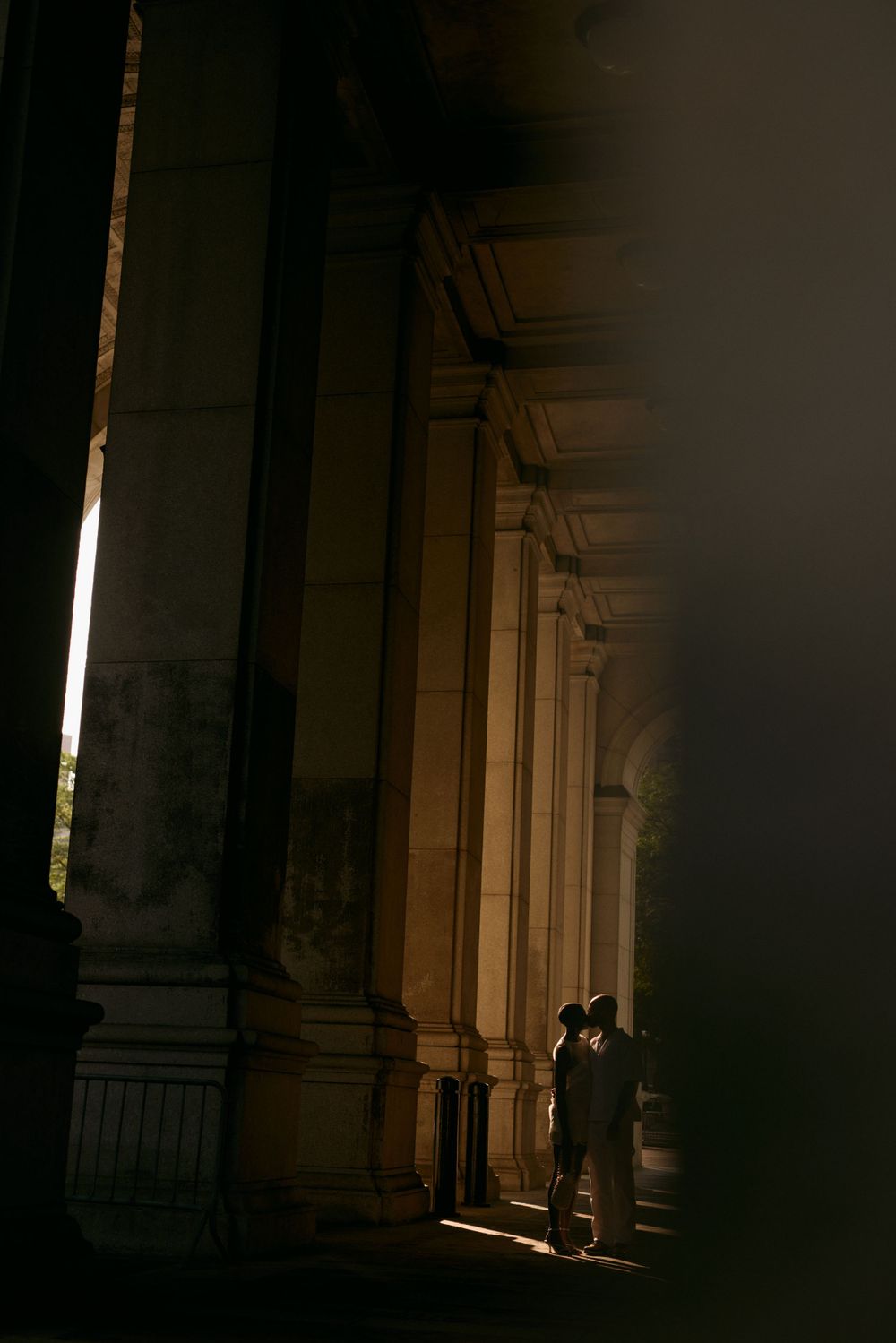 Dramatic lighting illuminates classical stone columns in dark interior space.